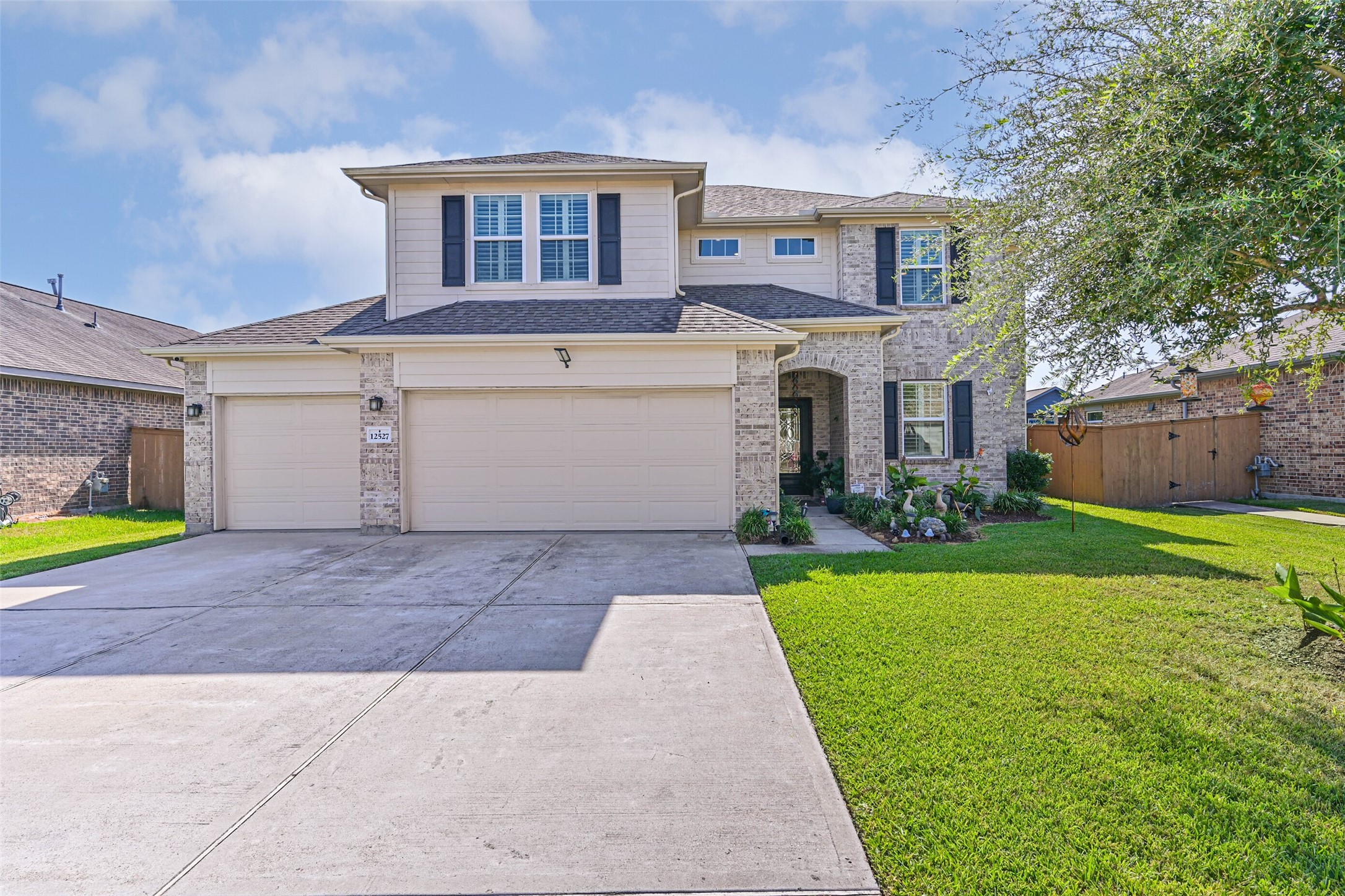 Welcoming front elevation showcasing the home's spacious driveway, landscaped lawn, and three-car garage.