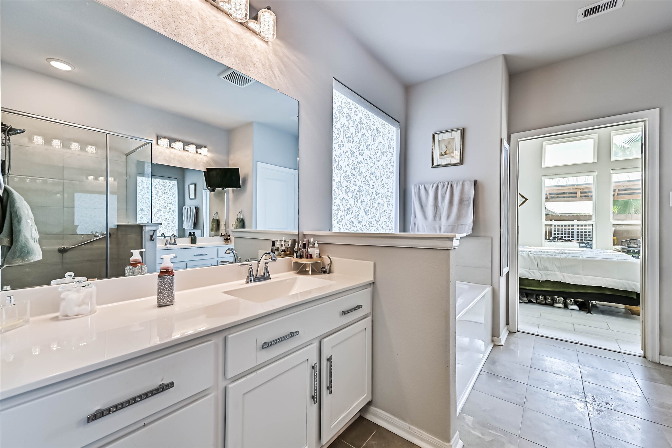 Additional view of the primary bathroom highlighting the generous counter space, soaking tub, and convenient access to the primary bedroom.