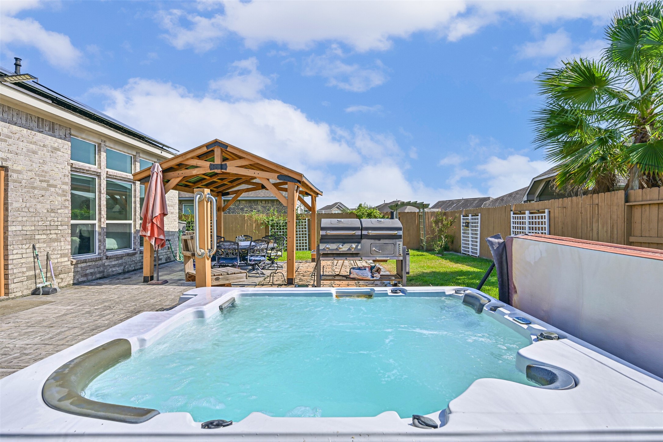 Expansive patio with a private hot tub and covered seating area, creating the perfect setting for relaxing evenings and weekend gatherings.