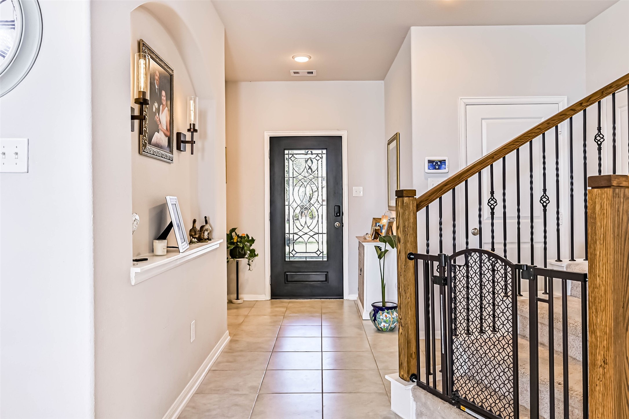 Elegant front entry showcasing a decorative glass front door, tile flooring, architectural accents, and beautiful staircase details.
