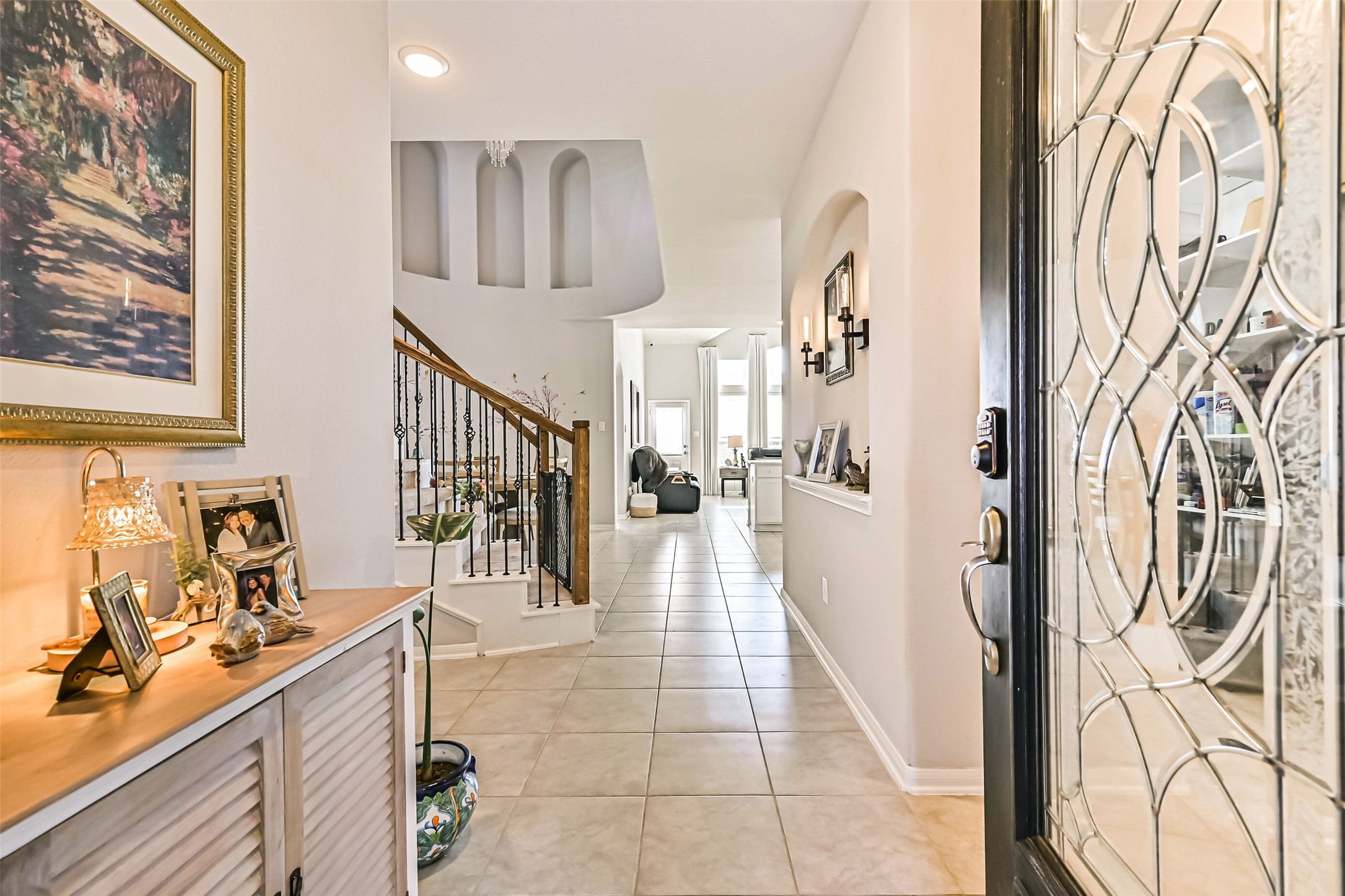 Welcoming entryway featuring tile flooring, decorative architectural niches, and an elegant staircase leading to the second floor.