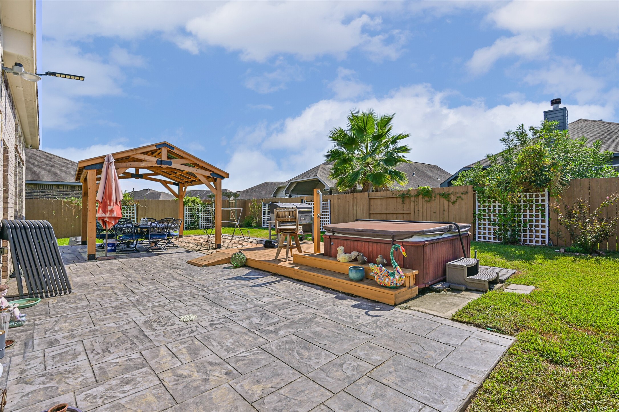 Another view of the beautifully designed backyard featuring a covered patio, private hot tub, and custom landscaping.