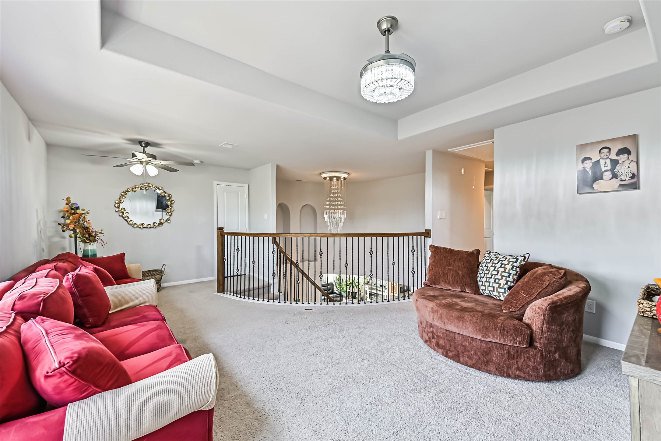 Spacious upstairs game room featuring tray ceilings, elegant lighting, and an open layout overlooking the first floor.