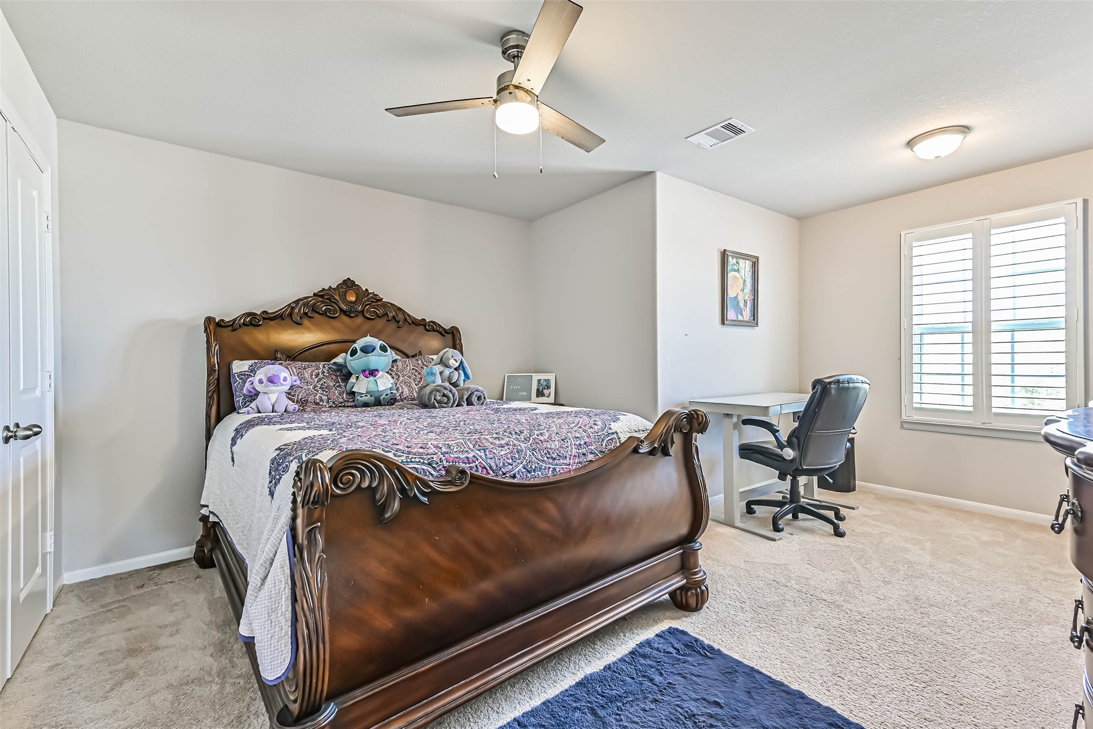 Generously sized secondary bedroom with ceiling fan, plantation shutters, and space for a desk or study area.