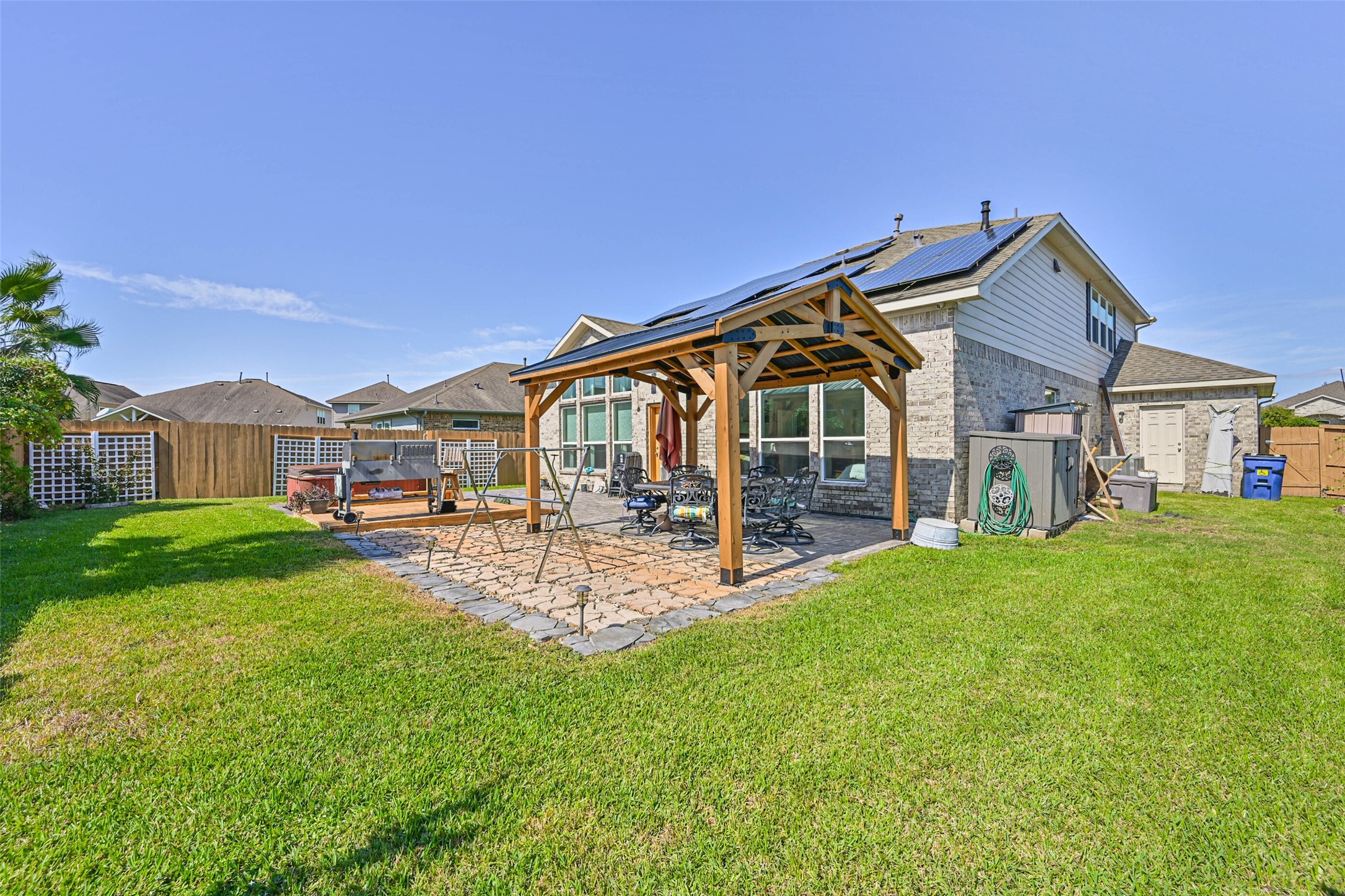 Inviting backyard oasis with a covered outdoor dining area, lush green lawn, and plenty of space to relax or entertain.