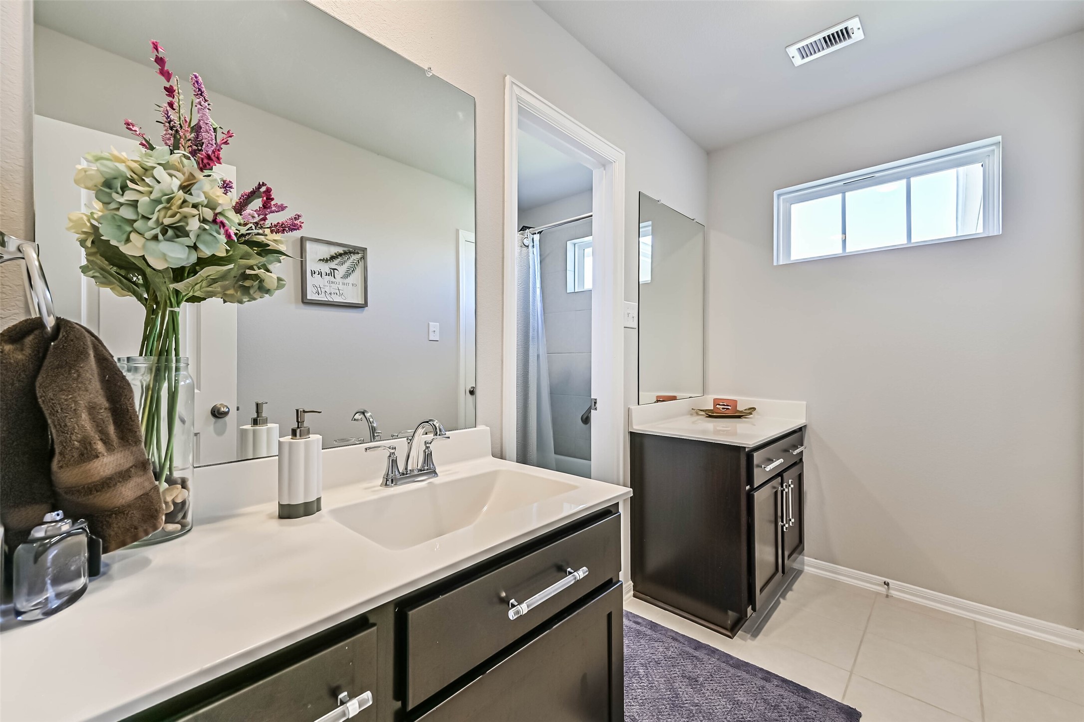 Spacious upstairs bathroom with dual vanities, ample cabinet storage, and a separate shower area.