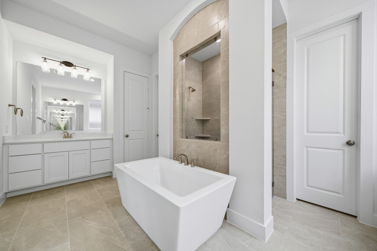 Bright and spacious primary bathroom designed with modern finishes and a relaxing soaking tub.