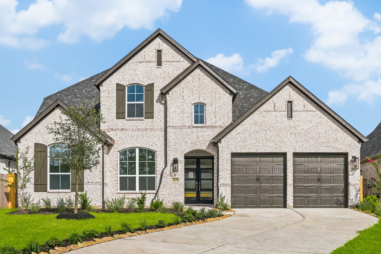 Elegant brick and stone elevation featuring timeless architecture, a covered entry, and a spacious 3-car garage.