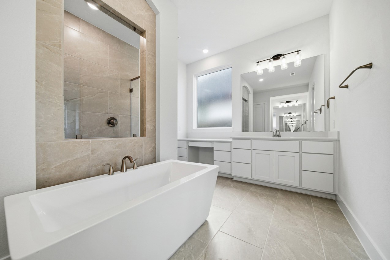 Spa-inspired primary bath with dual vanities, a freestanding tub, and a walk-in shower.