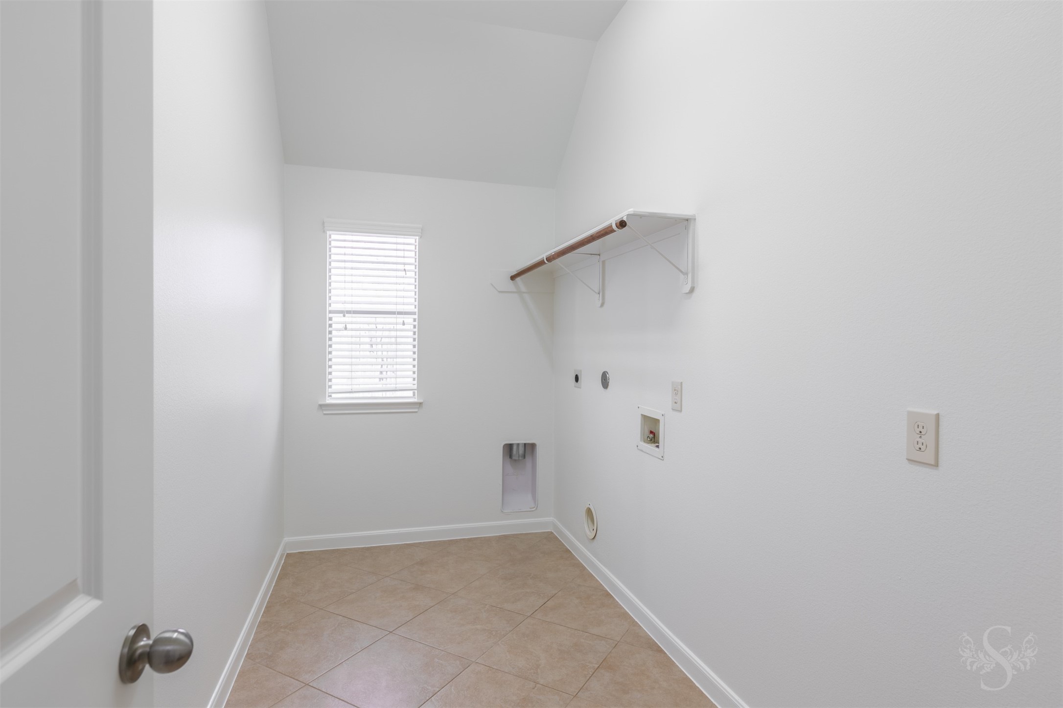 The spacious laundry room offers upper hanging space and room for full-size appliances, making everyday tasks simple and organized. Neutral finishes and a dedicated utility area add convenience to the homes thoughtful layout.