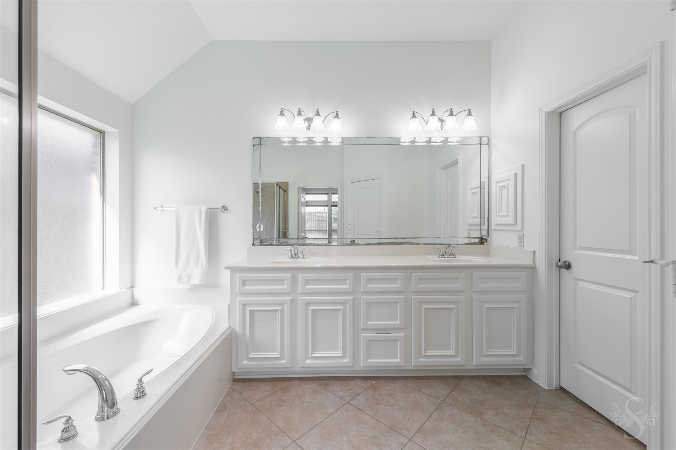 The spacious primary bath features an extended vanity with double sinks, a relaxing soaking tub, and a separate shower. A large mirror and abundant counter space enhance both style and convenience.