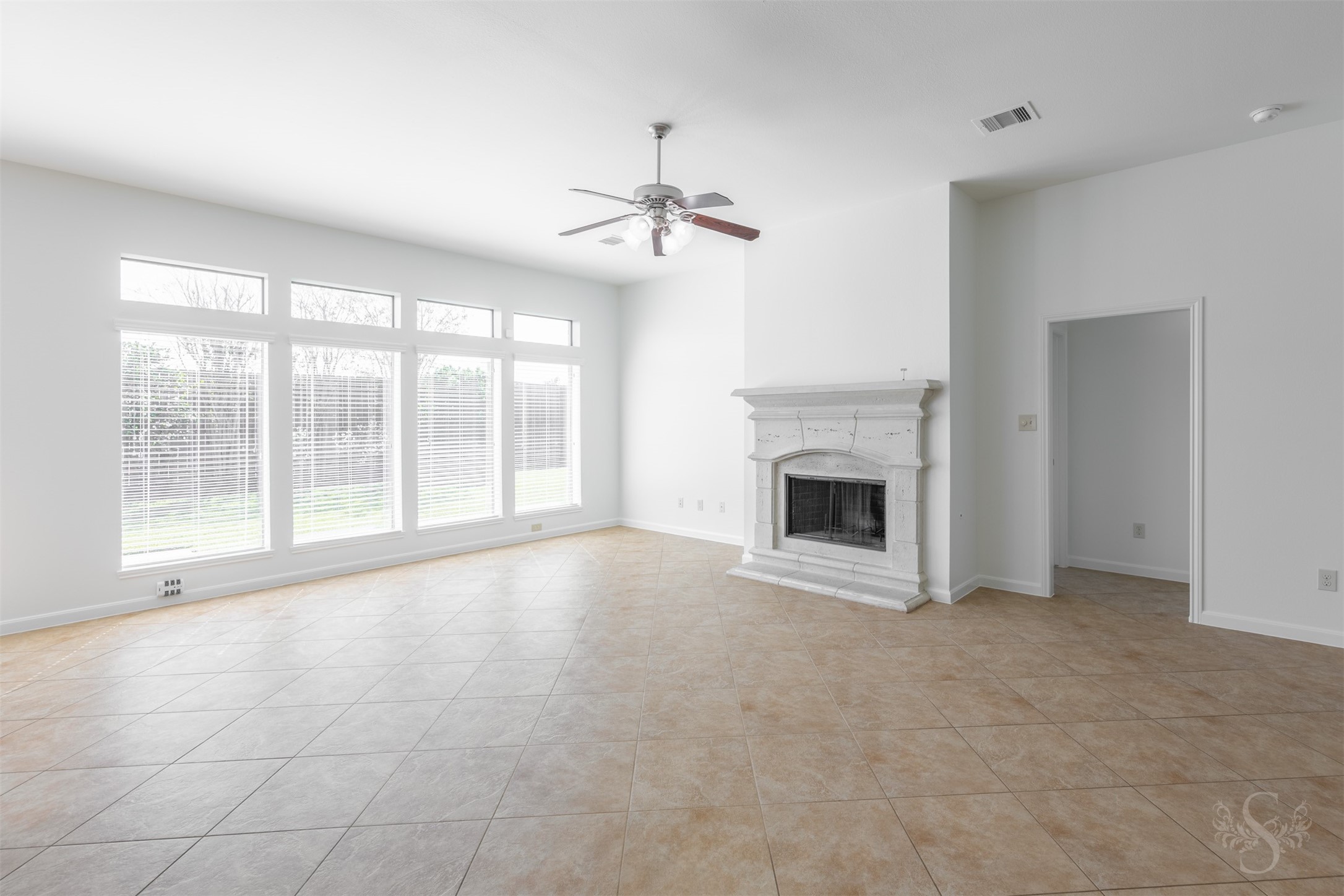 The spacious family room showcases a beautiful cast-stone fireplace and a wall of windows overlooking the back yard. High ceilings and diagonally laid tile flooring enhance this inviting space for everyday relaxation and entertaining friends. The spacious family room showcases a beautiful cast-stone fireplace and a wall of windows overlooking the back yard. High ceilings and diagonally laid tile flooring enhance this inviting space for everyday relaxation and entertaining friends.