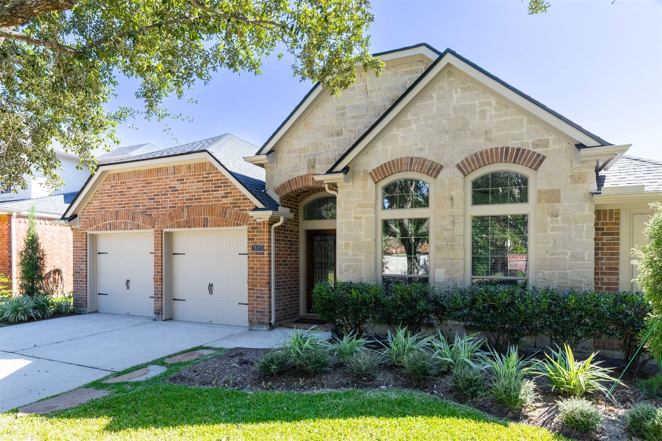 Beautiful brick and stonework, arched windows and layered gables give this home exceptional curb appeal. Mature trees and lush landscaping frame the welcoming covered entry.