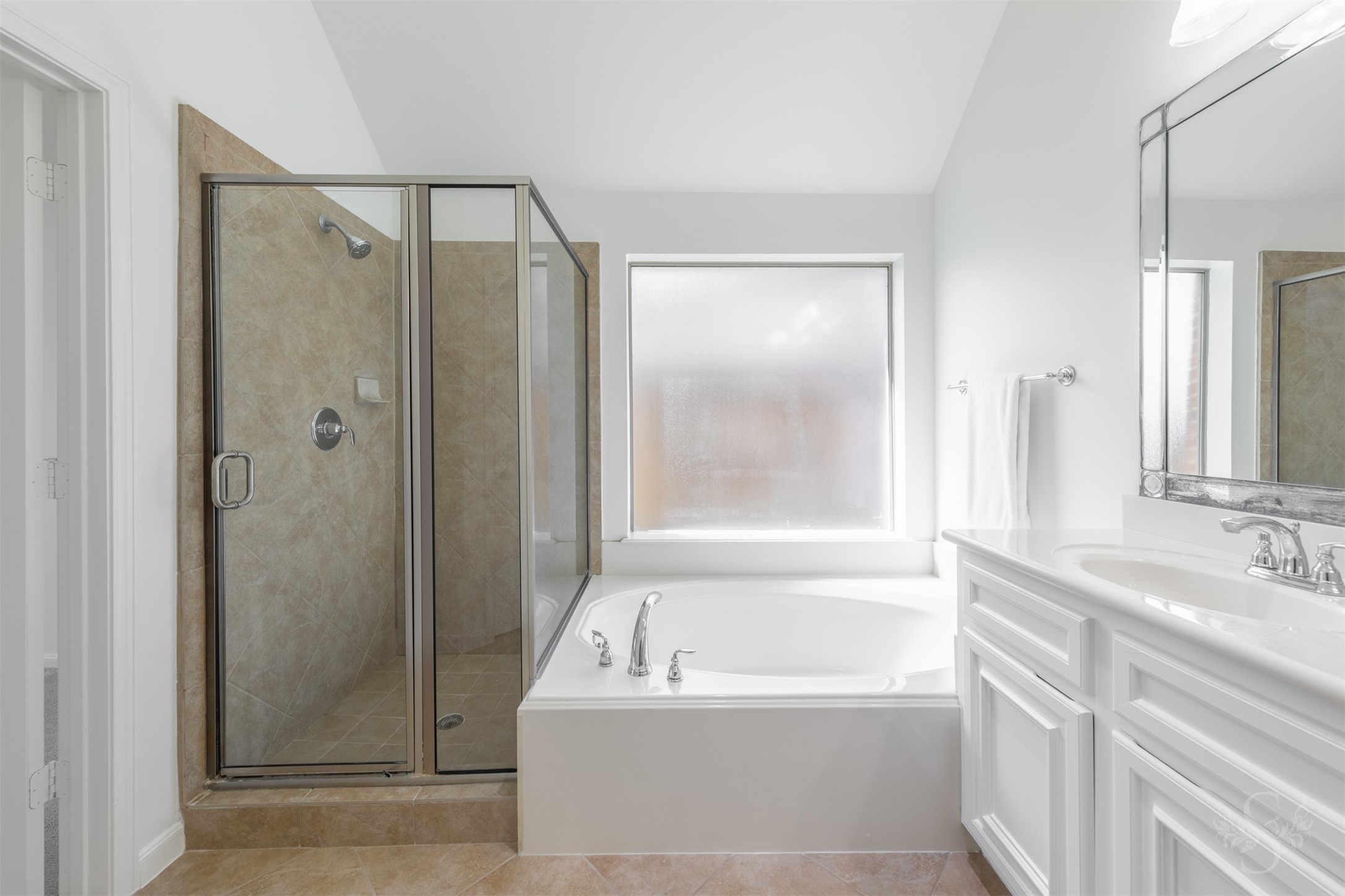 The spacious primary bath features an extended vanity with double sinks, a relaxing soaking tub, and a separate shower. A large mirror and abundant counter space enhance both style and convenience.
