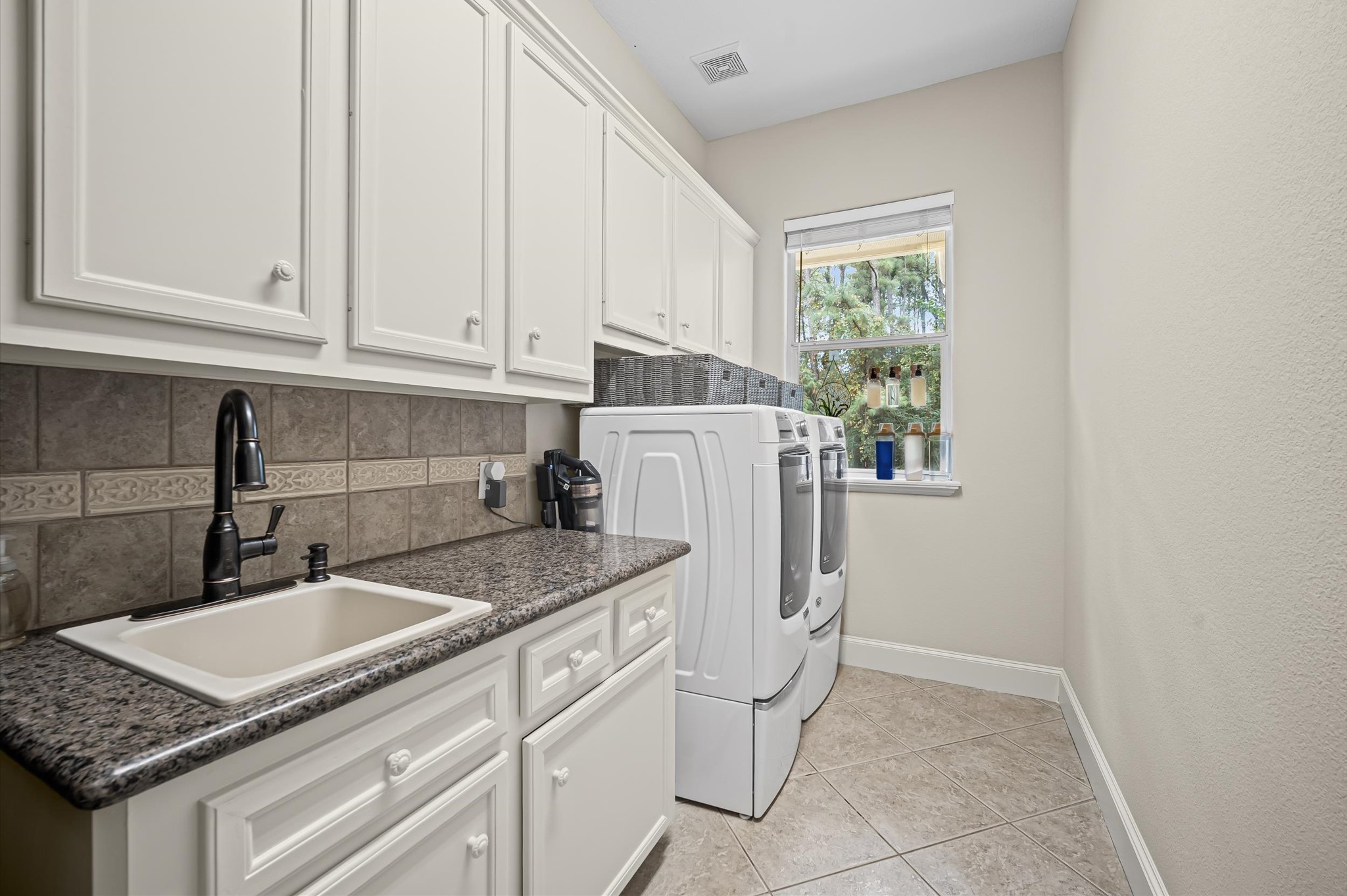Spacious laundry room with abundant cabinetry, folding counter and natural light