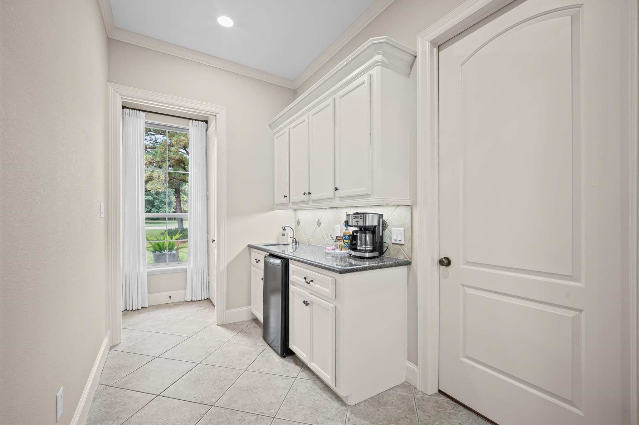 Conveniently appointed utility area with cabinetry, counter space and beverage refrigerator
