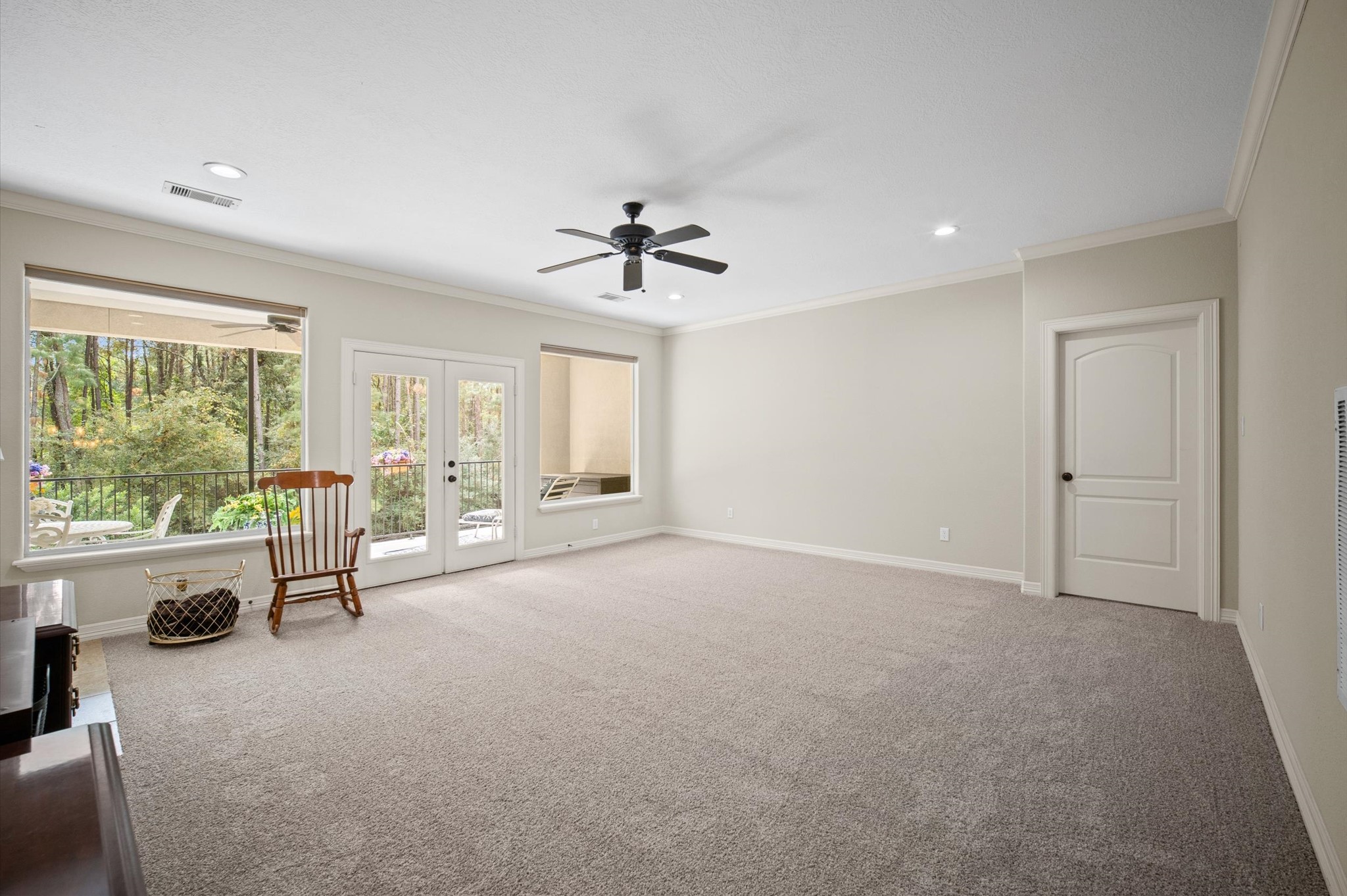 Spacious carpeted living area with built-in cabinetry and outdoor access