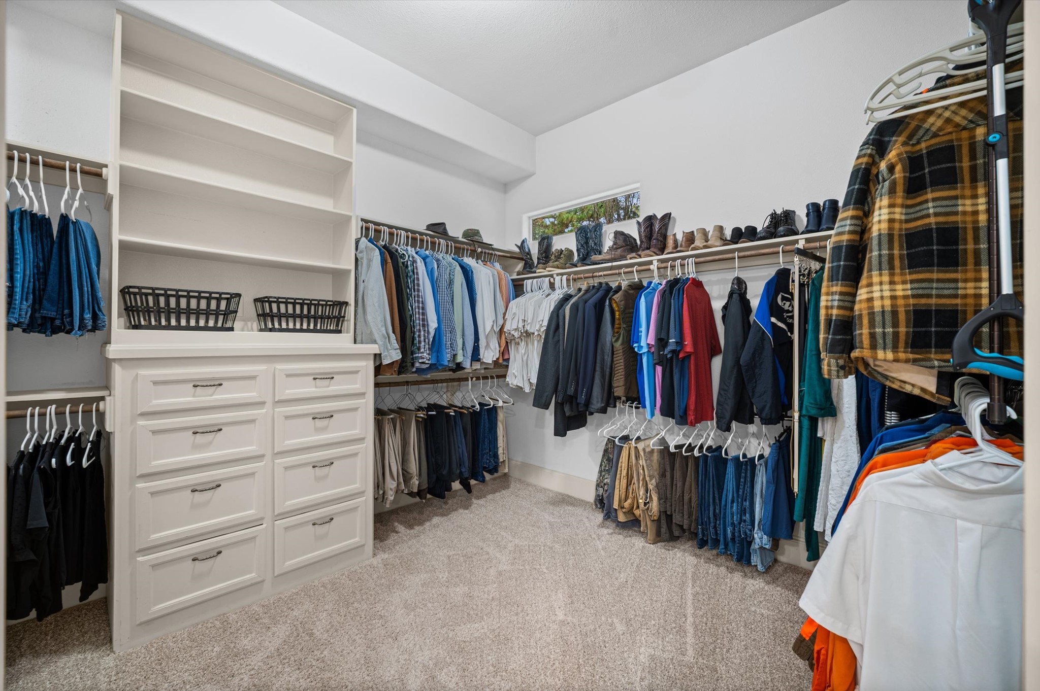 Generous walk-in primary closet with built-in shelving and drawers