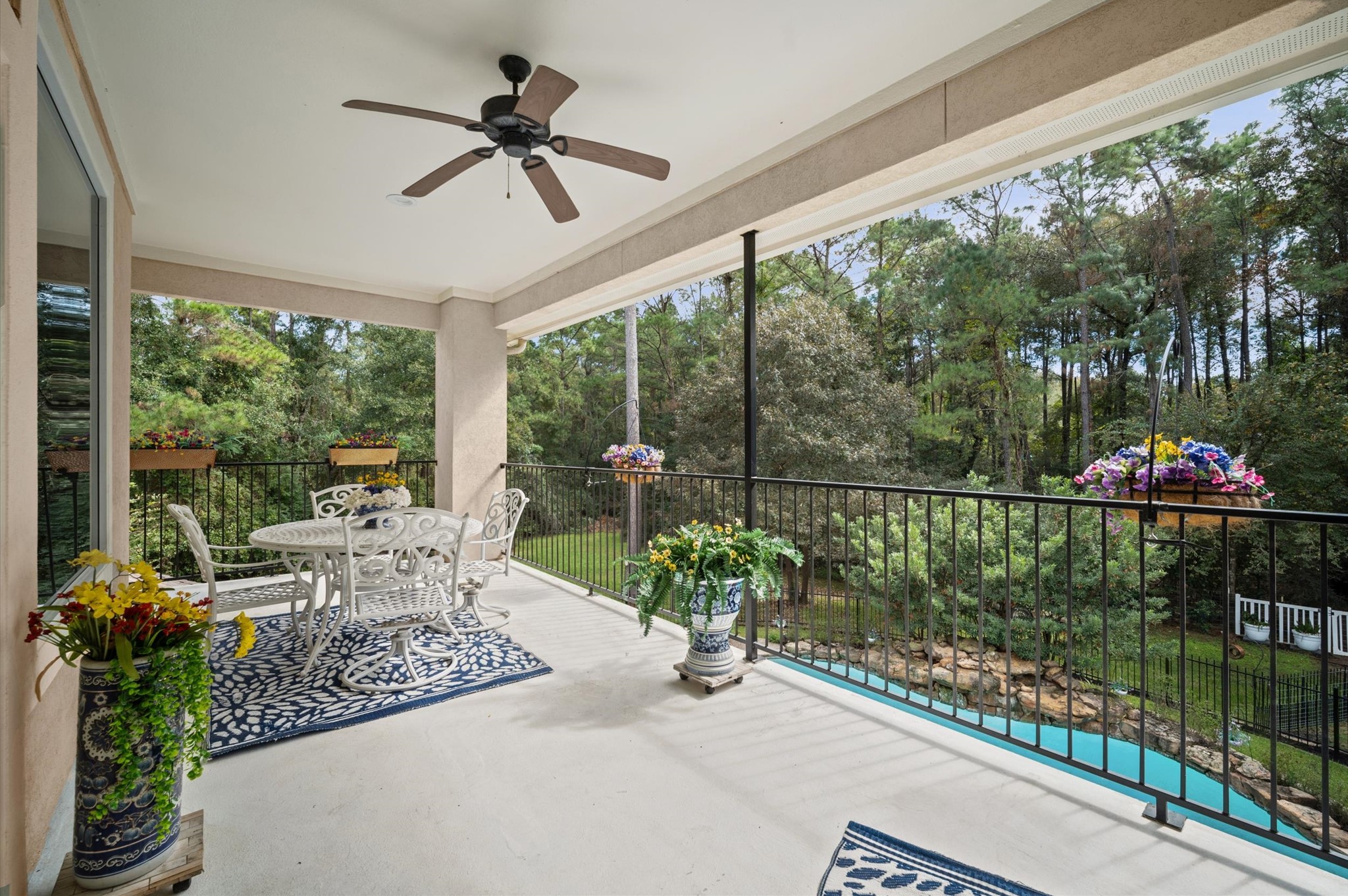 Covered upper-level balcony overlooking the pool and wooded backyard
