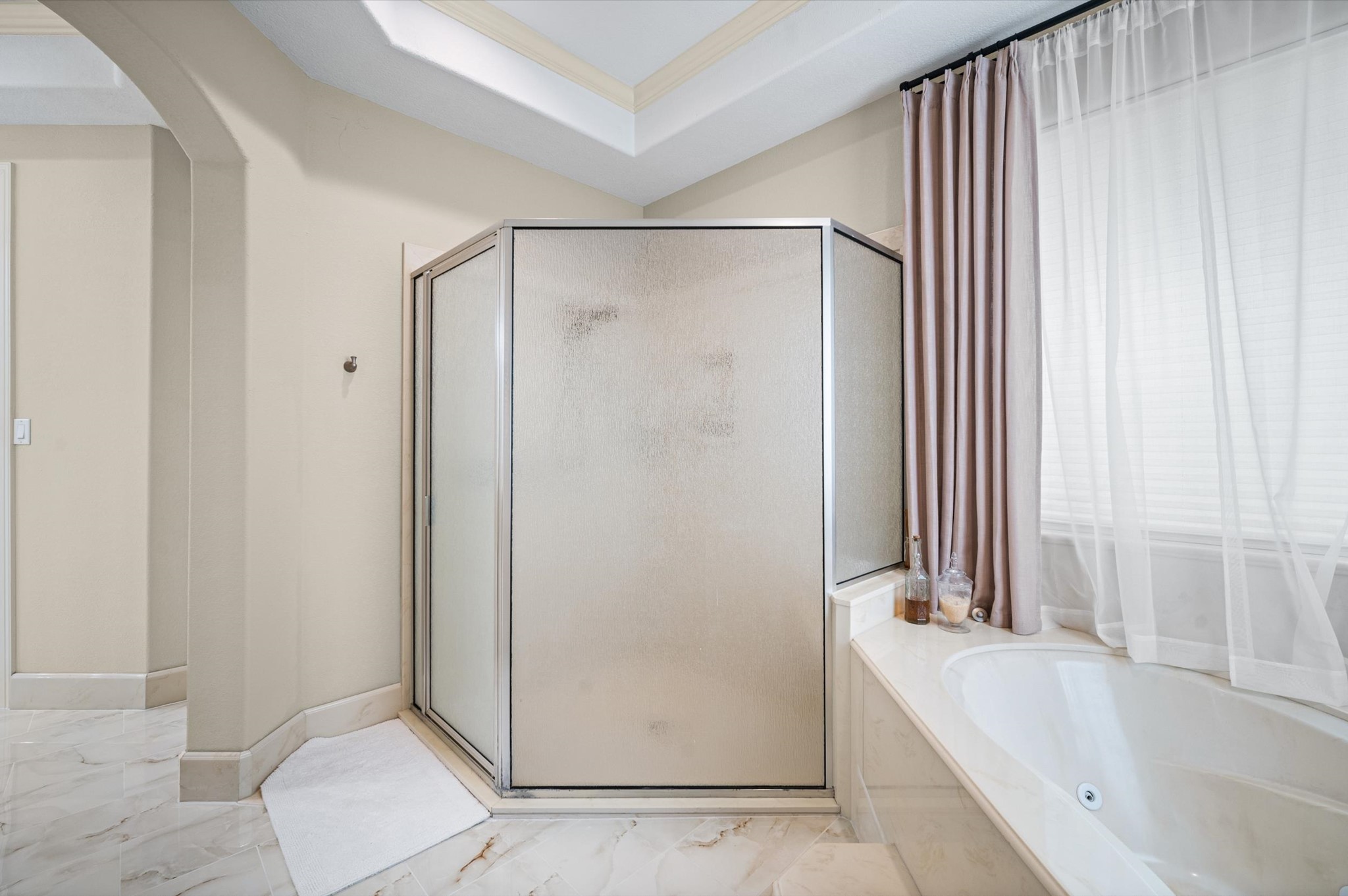 Primary bath featuring a separate glass-enclosed shower and soaking tub