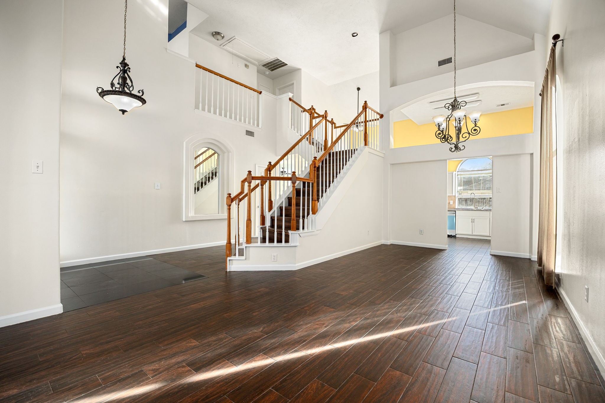 This versatile space flows seamlessly into the dining area, with a striking staircase and chandelier adding architectural charm throughout.