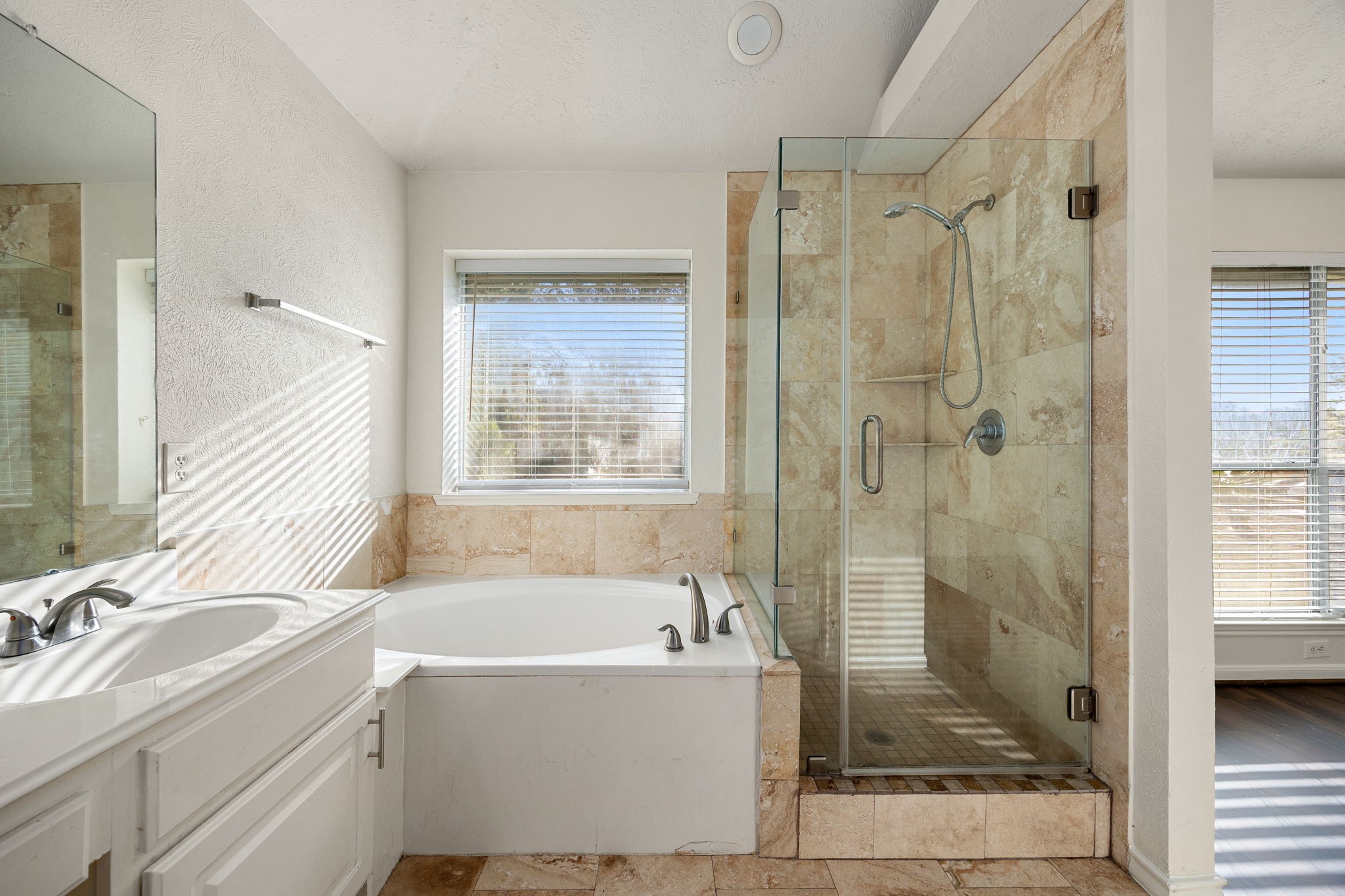 A relaxing corner soaking tub pairs beautifully with the separate glass-enclosed shower, creating a true spa-like retreat within the ensuite bath.