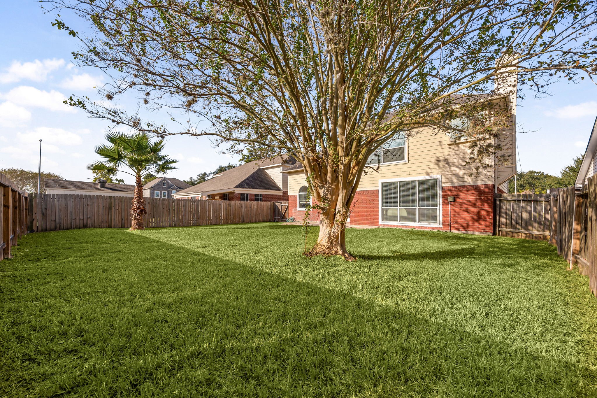 The expansive backyard offers a lush lawn and mature trees, creating a private outdoor retreat.