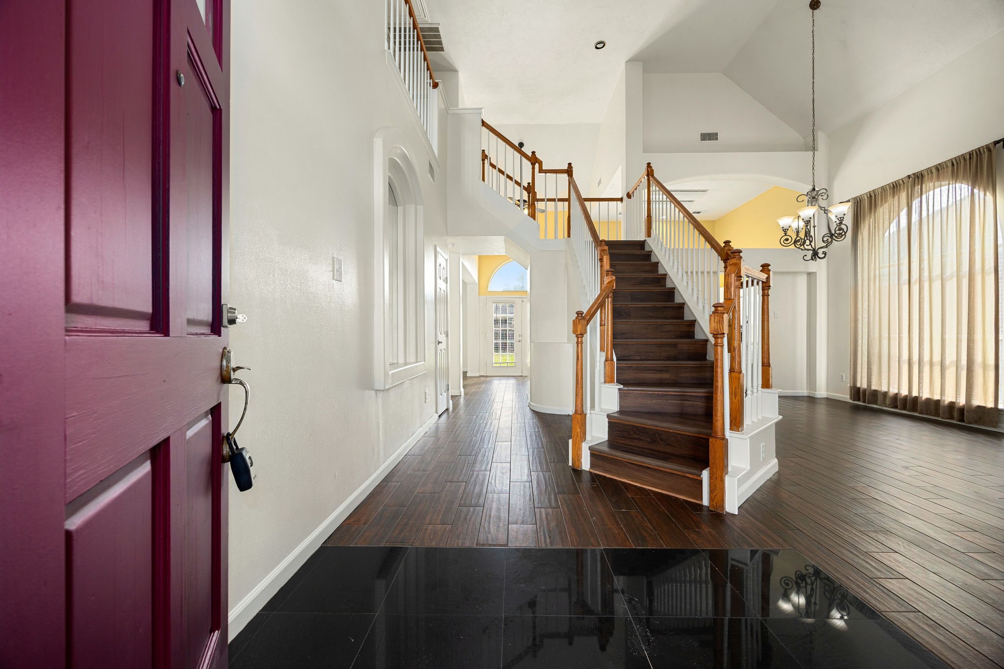 A dramatic two-story foyer welcomes you in, featuring a rich wood staircase, soaring ceilings, and an elegant chandelier that sets the tone for the home.