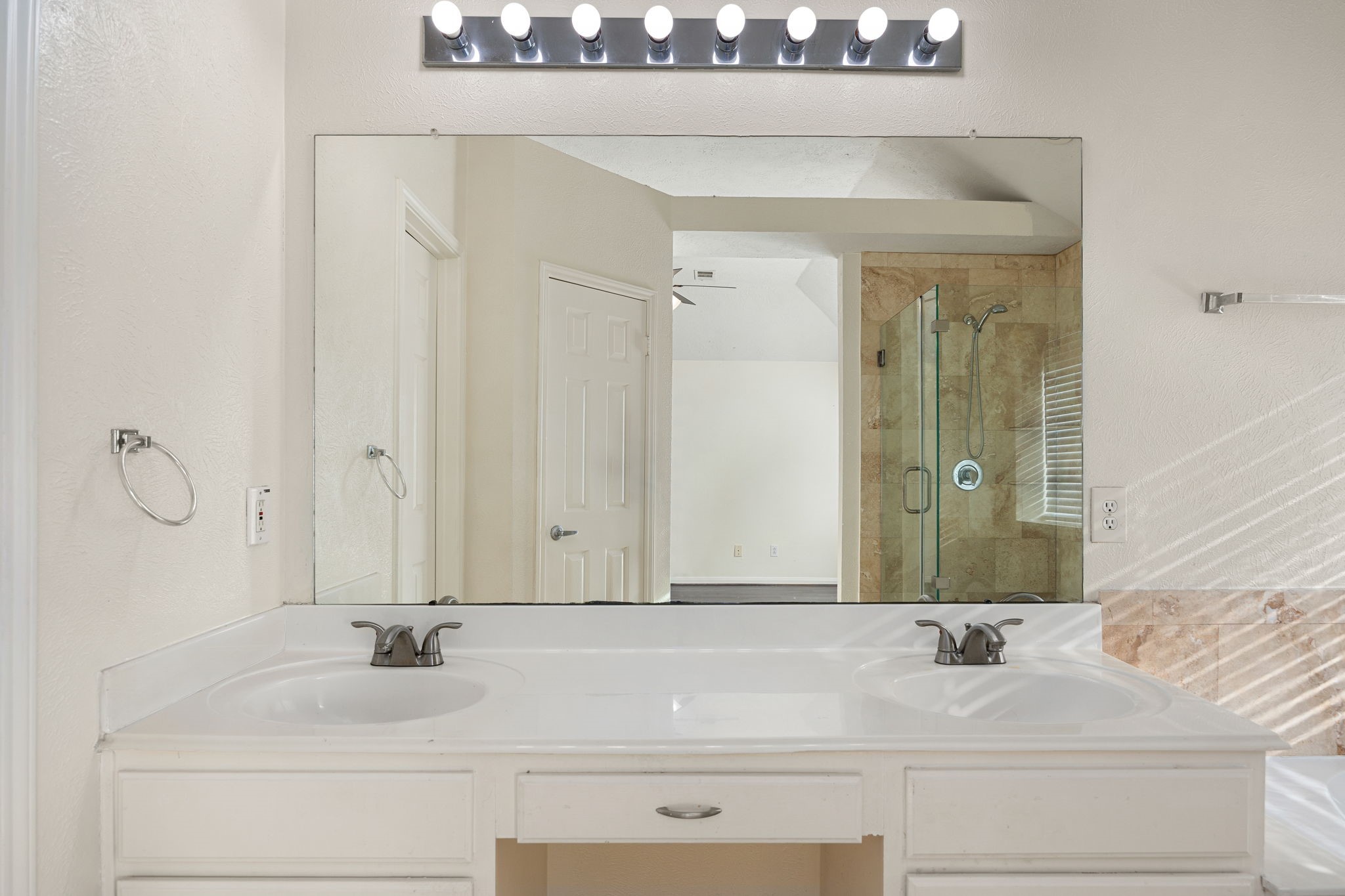 The ensuite bath offers a dual-sink vanity with plenty of counter space and a large mirror for added brightness.