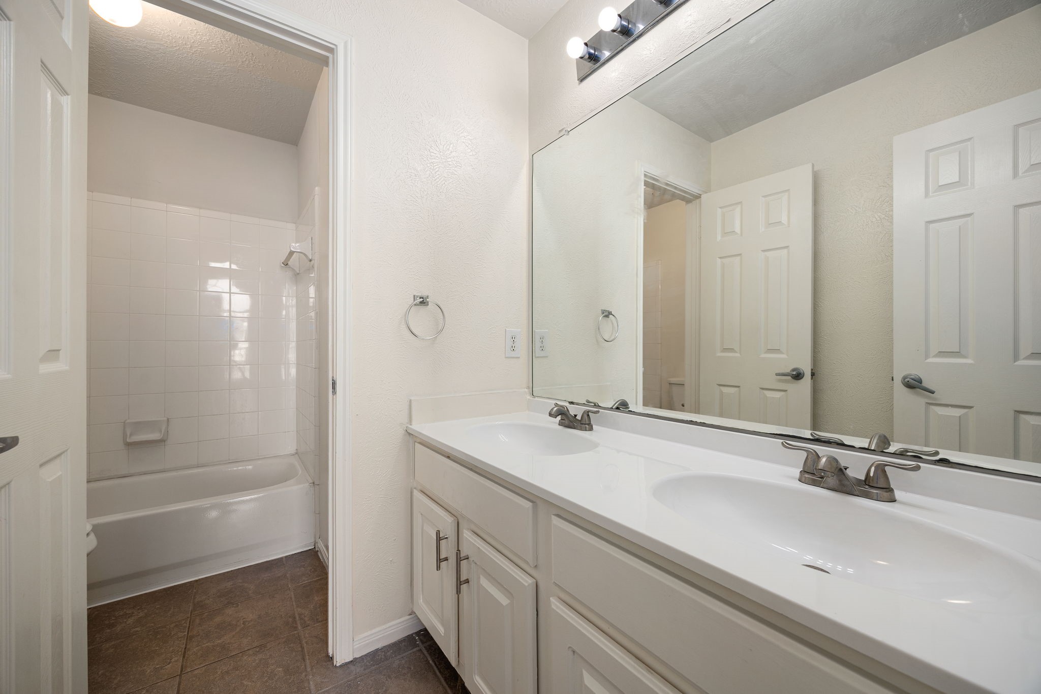 A secondary bathroom offers a tub-shower combo and dual-sink vanity, providing convenience for family or guests.