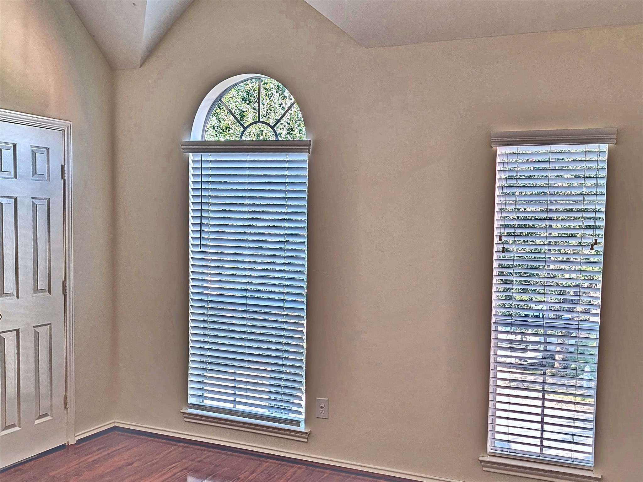 Upstairs bedroom with architectural vaulted ceiling and arched window.