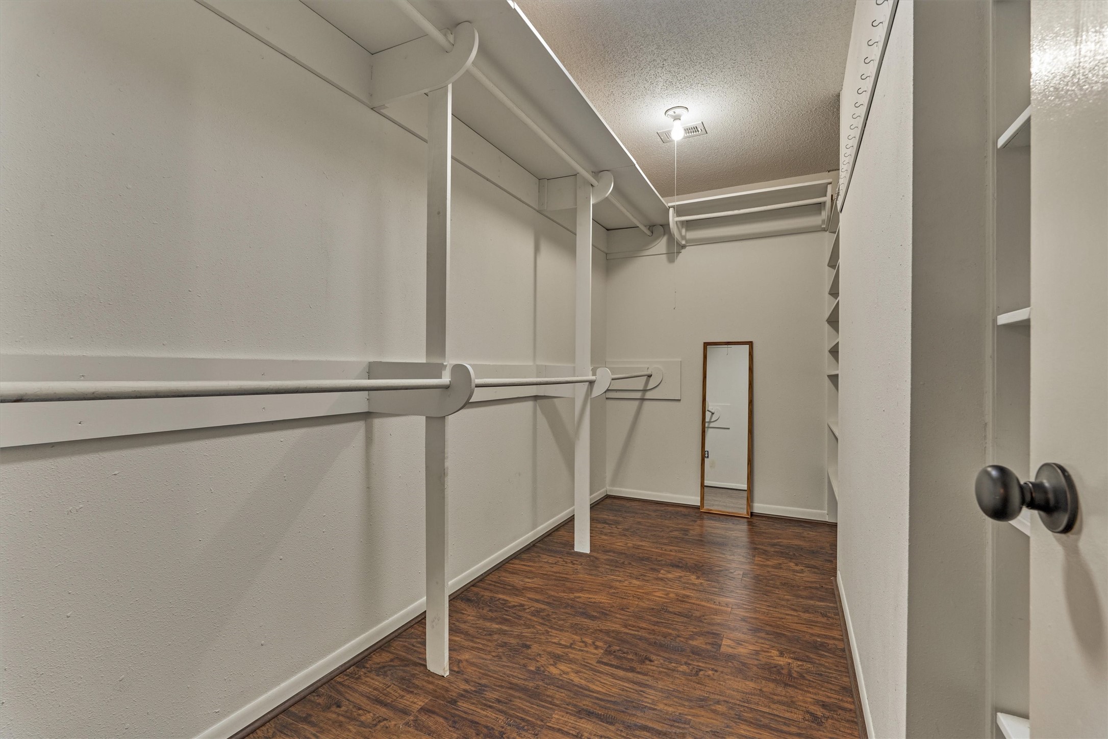 Spacious walk-in closet featuring built-in shelving and multiple hanging racks, offering plenty of storage and organization options to fit your needs.