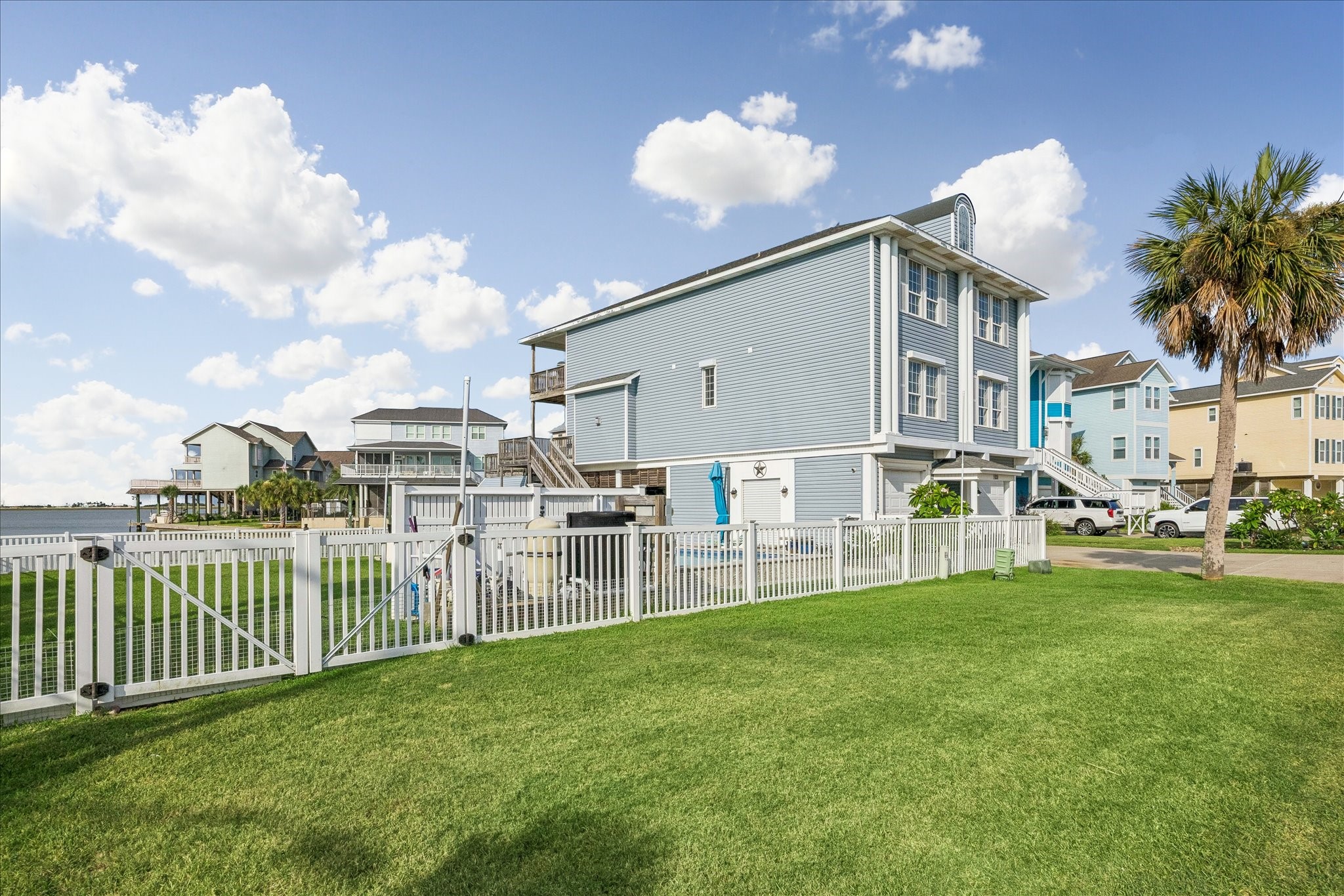 Fully fenced yard with new vinyl fencing for enclosure with three new gates & locks. Side view of the home showing the defined outdoor space.