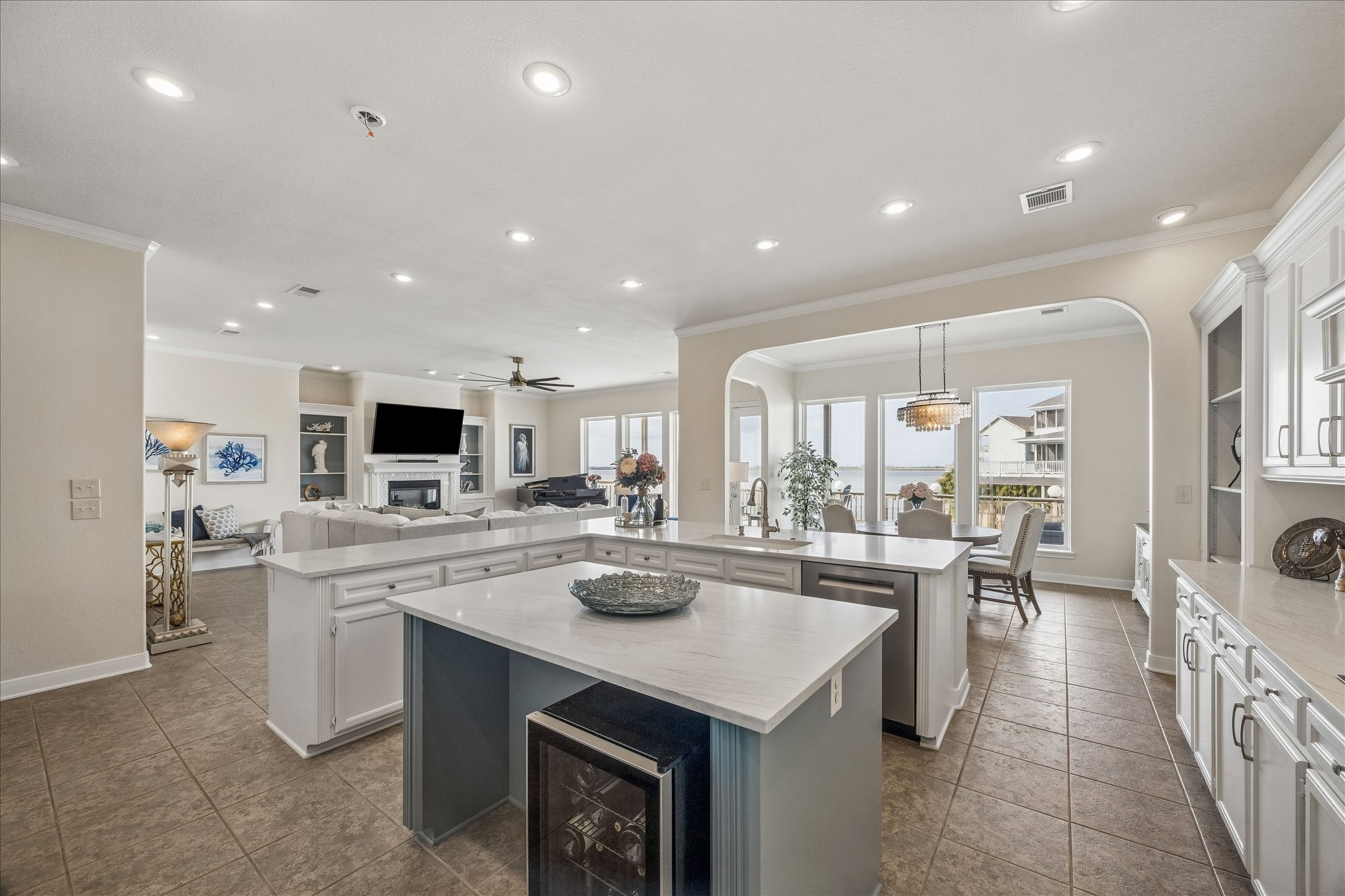 Open kitchen with tile flooring flowing into the living and dining areas, creating a cohesive entertaining space. A large walk-in pantry offers abundant storage, additional shelving, and a built-in spice rack. Additional features include a beverage refrigerator, abundant cabinetry, and easy access to the waterfront views.