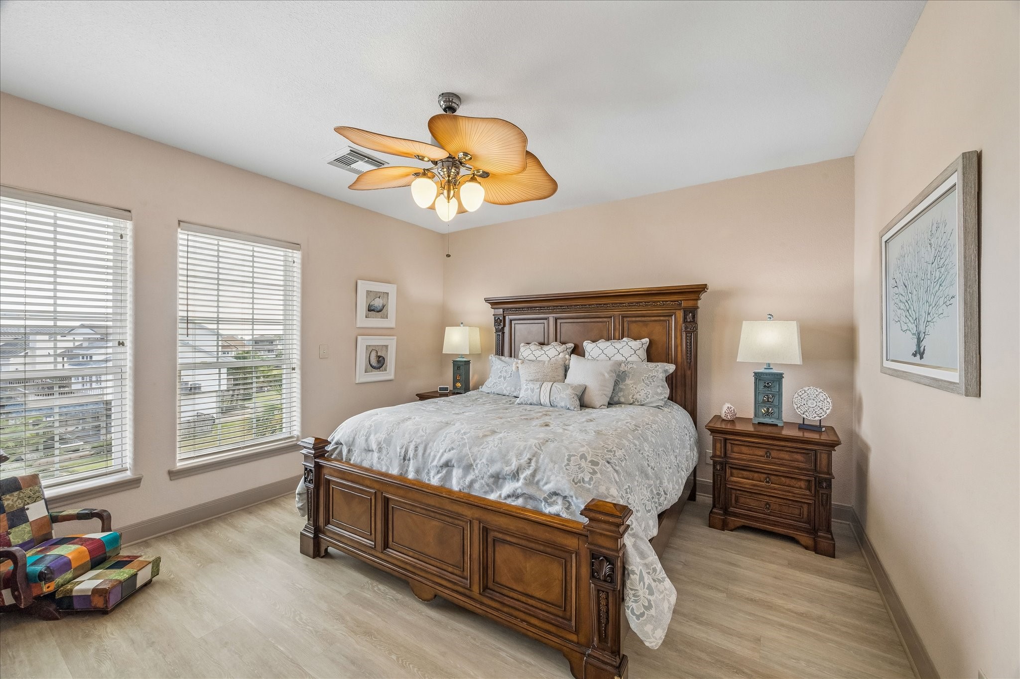 3rd level guest bedroom with laminate wood flooring, a walk-in closet, and convenient access to a full guest bathroom. Front-facing windows provide natural light and views overlooking the front of the home.