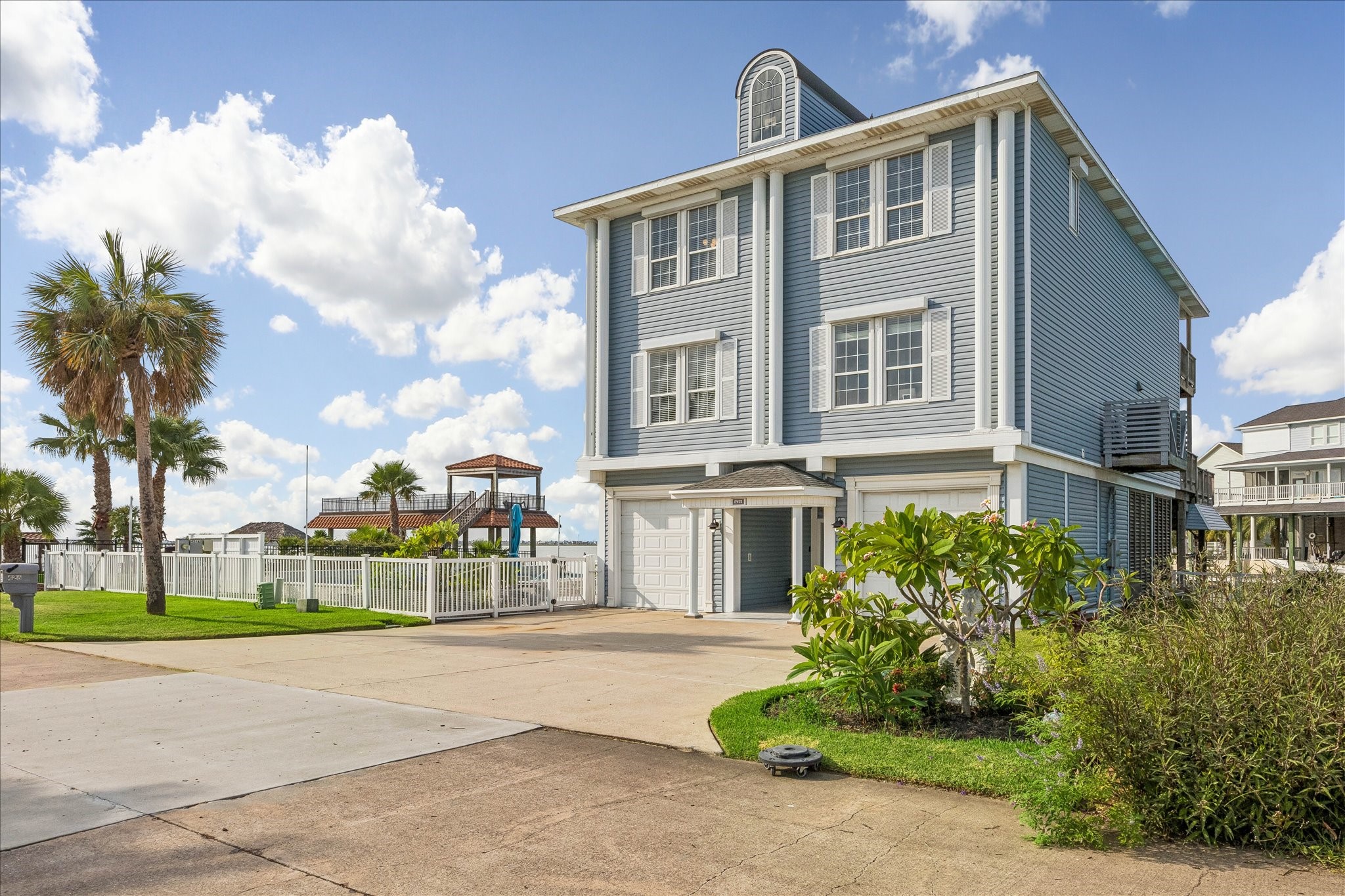 Large windows complete with storm shutters throughout the home, spacious driveway, two single car garages nestled in a beautifully landscaped setting with palm trees and vibrant greenery. All shutters have recently been serviced.