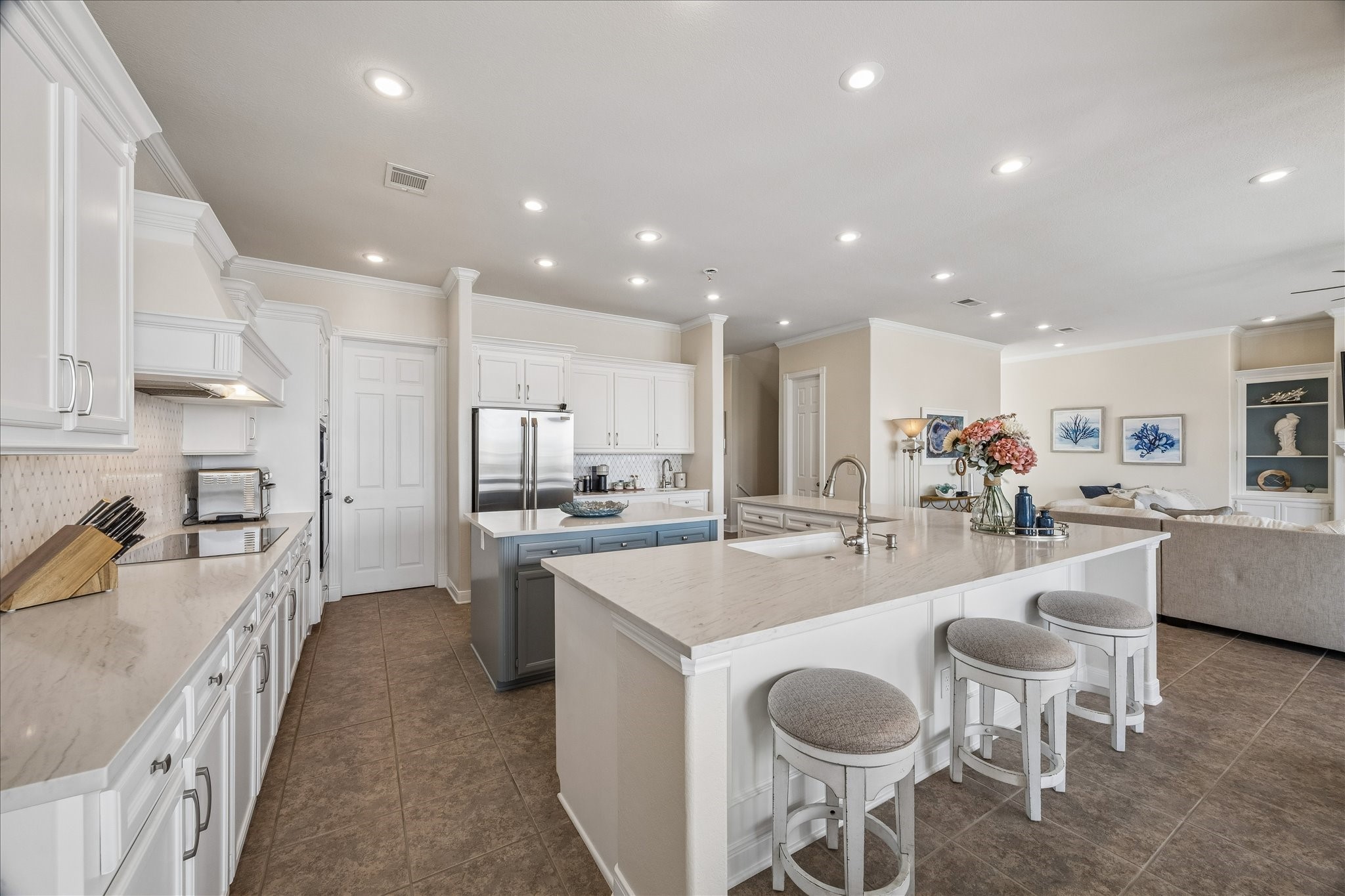 Gourmet kitchen featuring quartz countertops, a large center island with ample storage, breakfast bar seating, and dual sinks, including a dedicated prep sink.