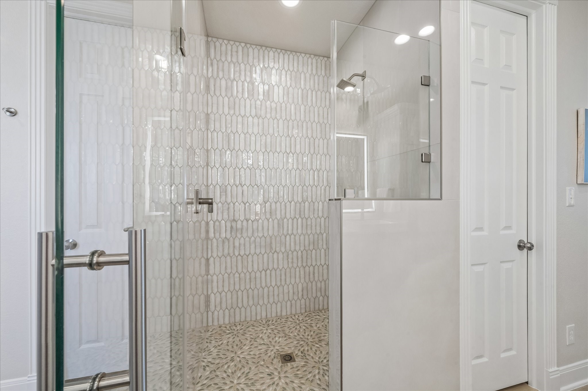 Completely remodeled walk-in shower featuring new tile, a generous shower area, and discreet built-in shelving for convenient storage.
