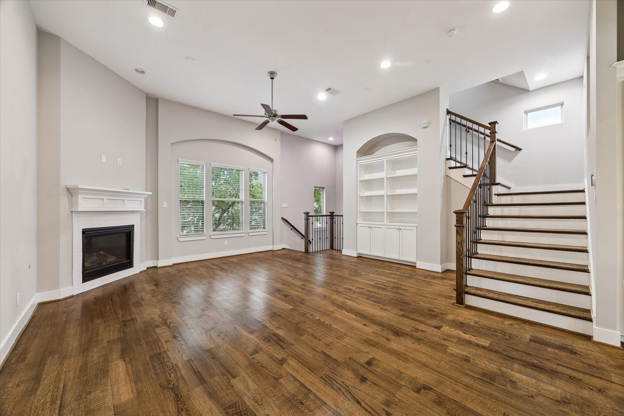 Large living room with a gas fireplace, tall ceilings, and built-ins. There is room for a dining table in front of the built-ins.