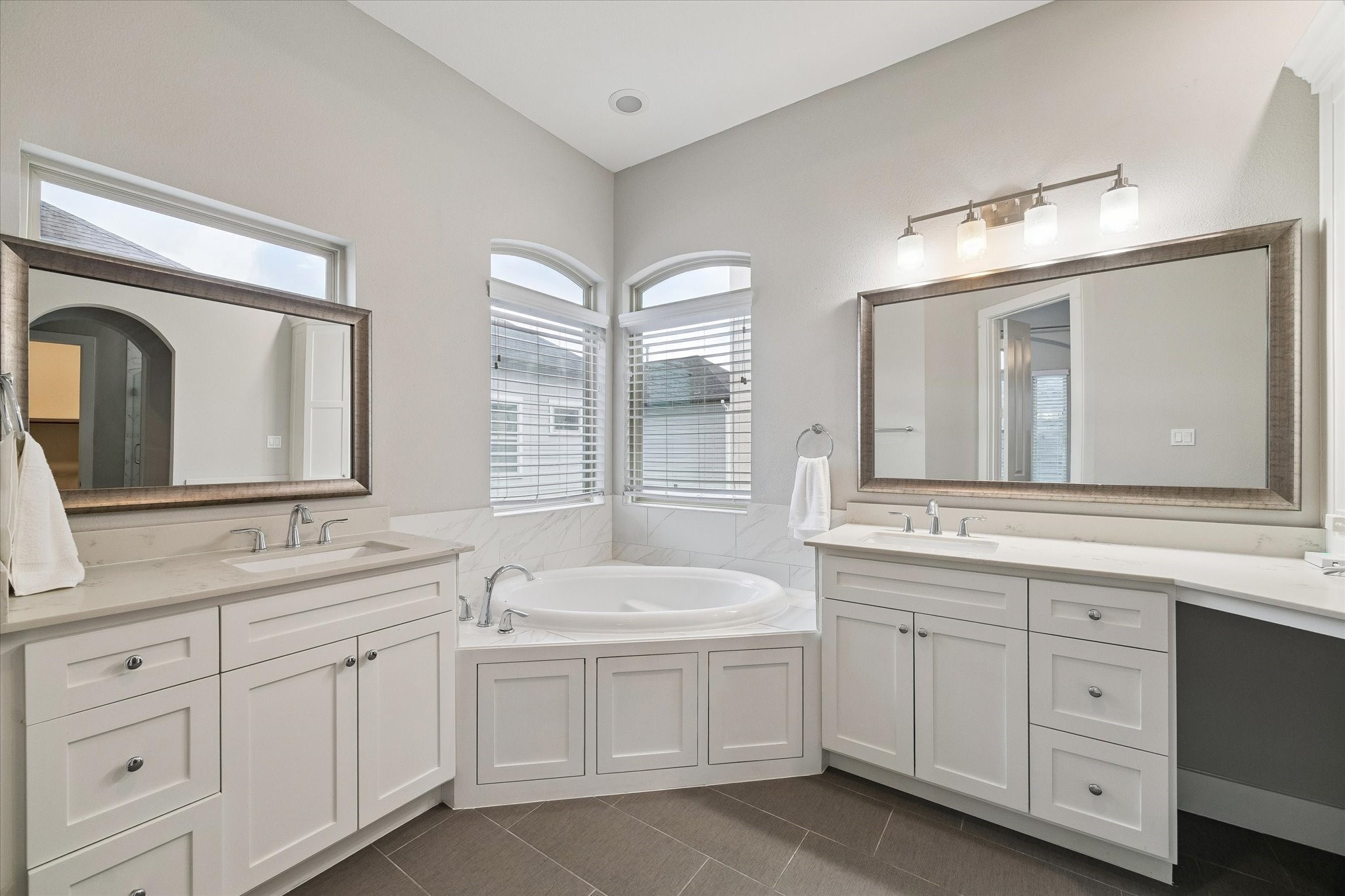 Spa-like primary bathroom with separate sinks, a vanity, a soaking tub, a water closet, and a shower.