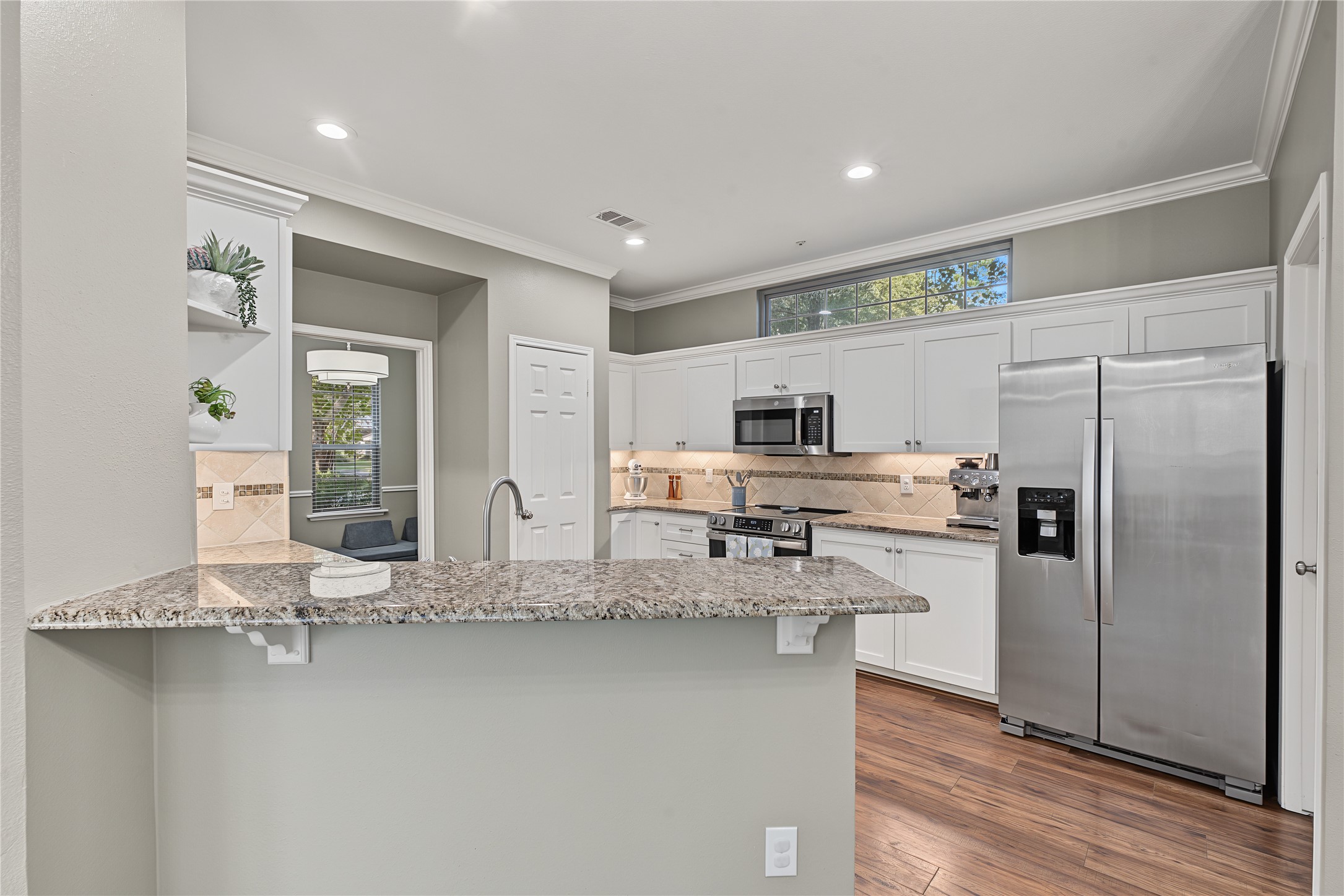 This kitchen features a breakfast bar, granite countertops, and an abundance of natural light.