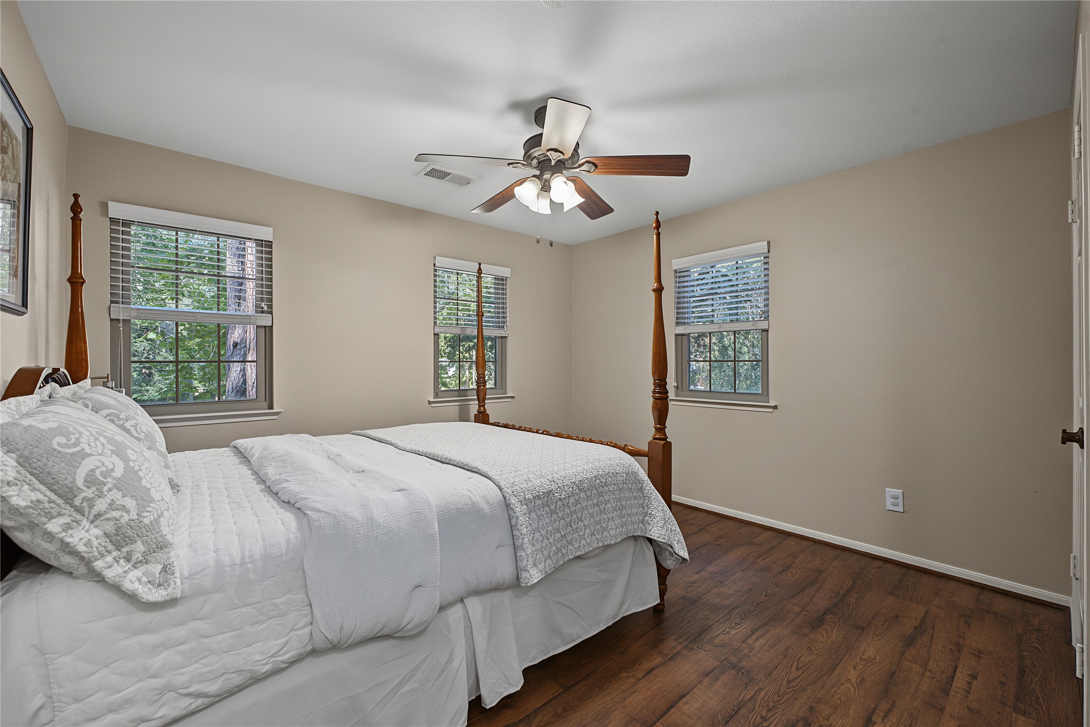 Another secondary bedroom featuring abundant natural light from three large windows.