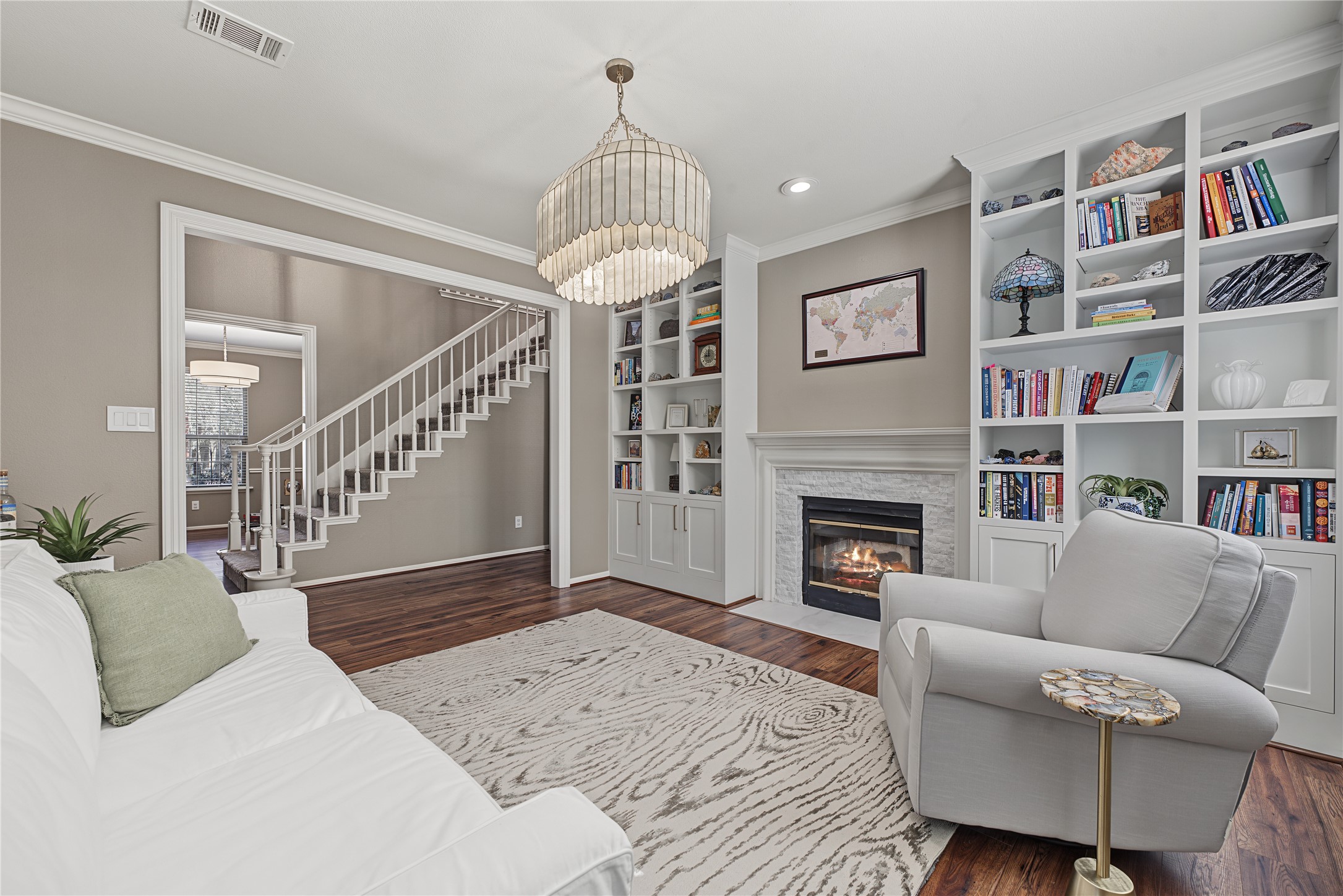 Front sitting room featuring custom built-in shelving and a dual-sided fireplace that opens into the living room.