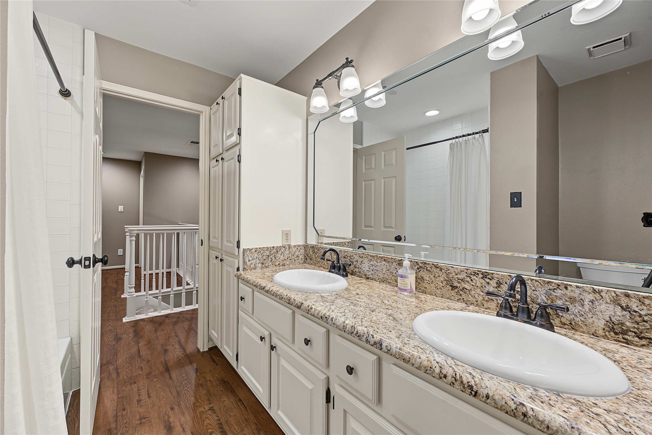 Upstairs full bathroom featuring a convenient double-sink vanity and ample cabinetry.