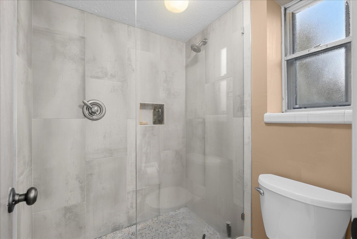Primary bathroom features a tiled walk-in shower with glass enclosure and recessed niche.