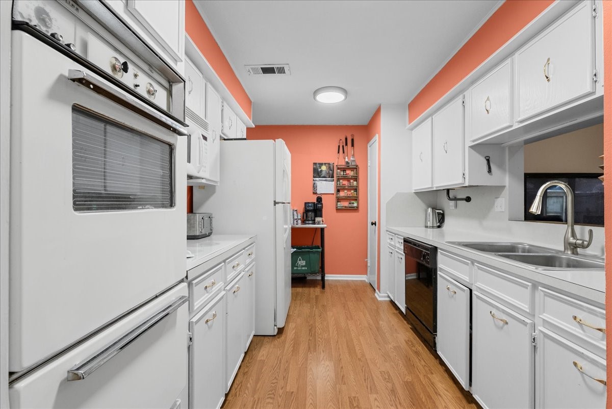Galley-style kitchen with abundant white cabinetry, built-in oven, and microwave. Galley-style kitchen with abundant white cabinetry, built-in oven, and microwave.