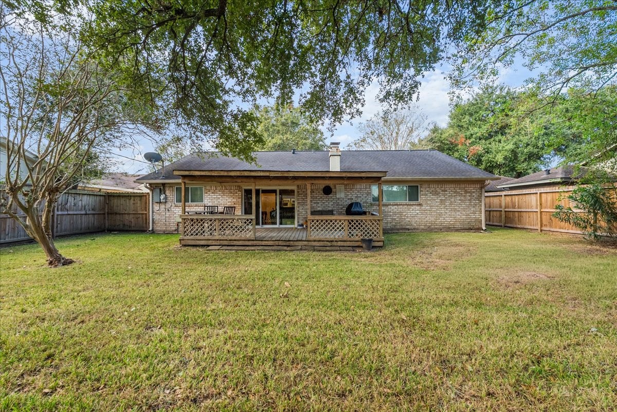 Rear exterior showcasing the covered wood deck and generously sized fenced backyard. Rear exterior showcasing the covered wood deck and generously sized fenced backyard.
