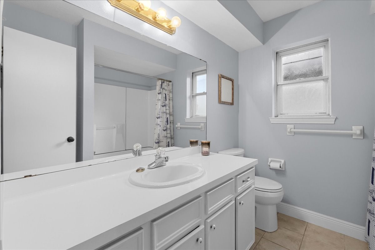 Secondary bathroom with white vanity cabinetry, generous counter space, and tub/shower combination.