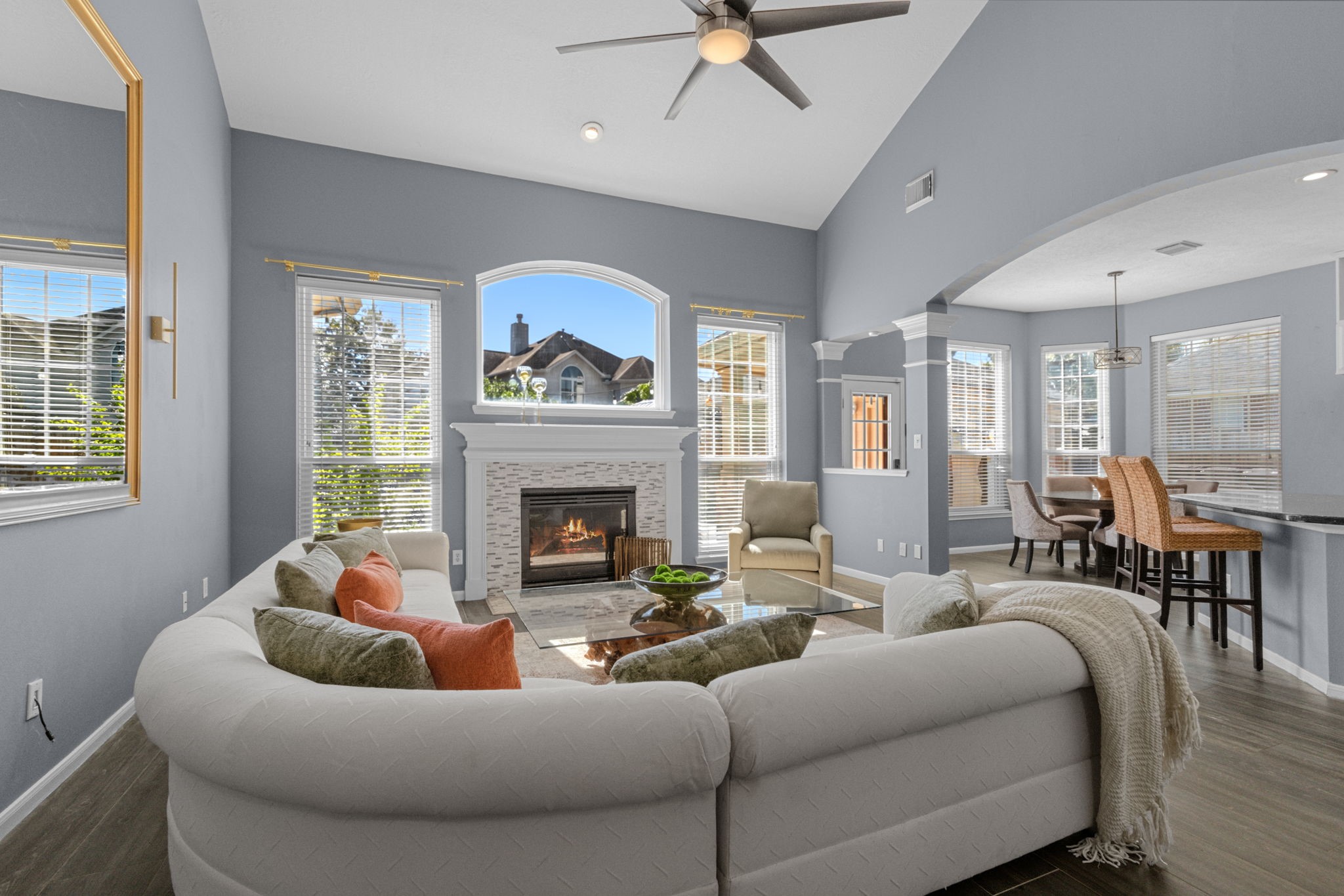 Spacious family room with high ceilings and abundant natural light features a cozy fireplace, seamlessly connecting to an inviting dining space. Spacious family room with high ceilings and abundant natural light features a cozy fireplace, seamlessly connecting to an inviting dining space.