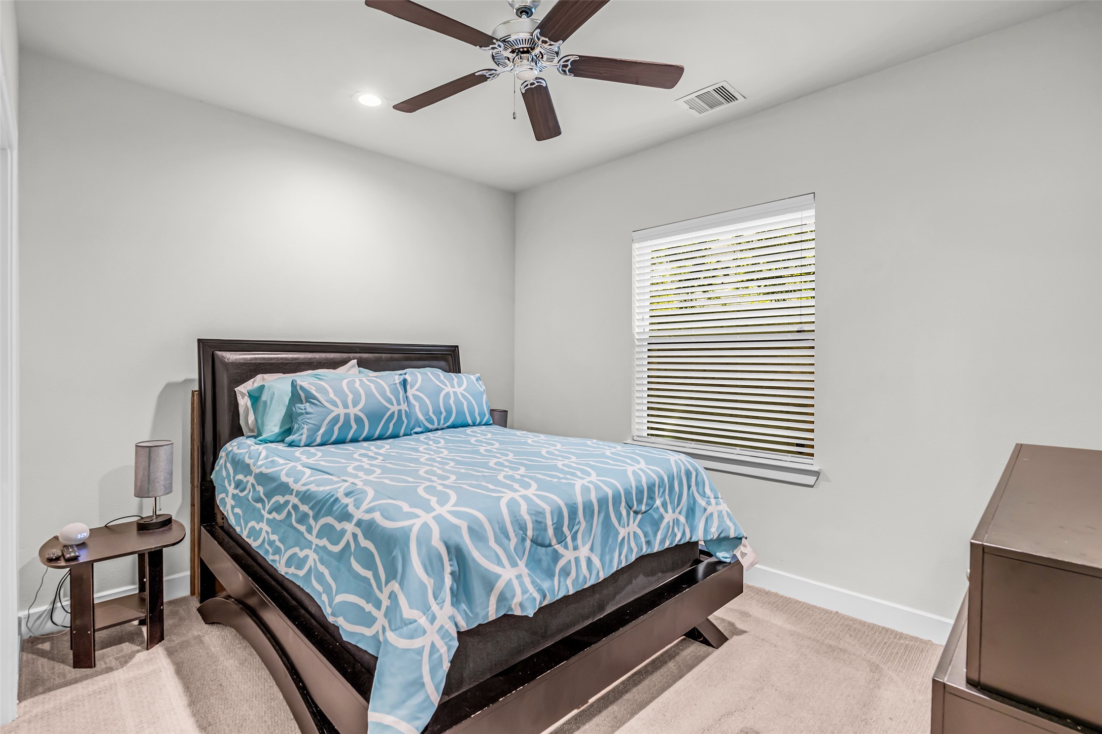 Additional secondary room located on the first floor, featuring carpeted flooring, a ceiling fan, and a window with views of the backyard.